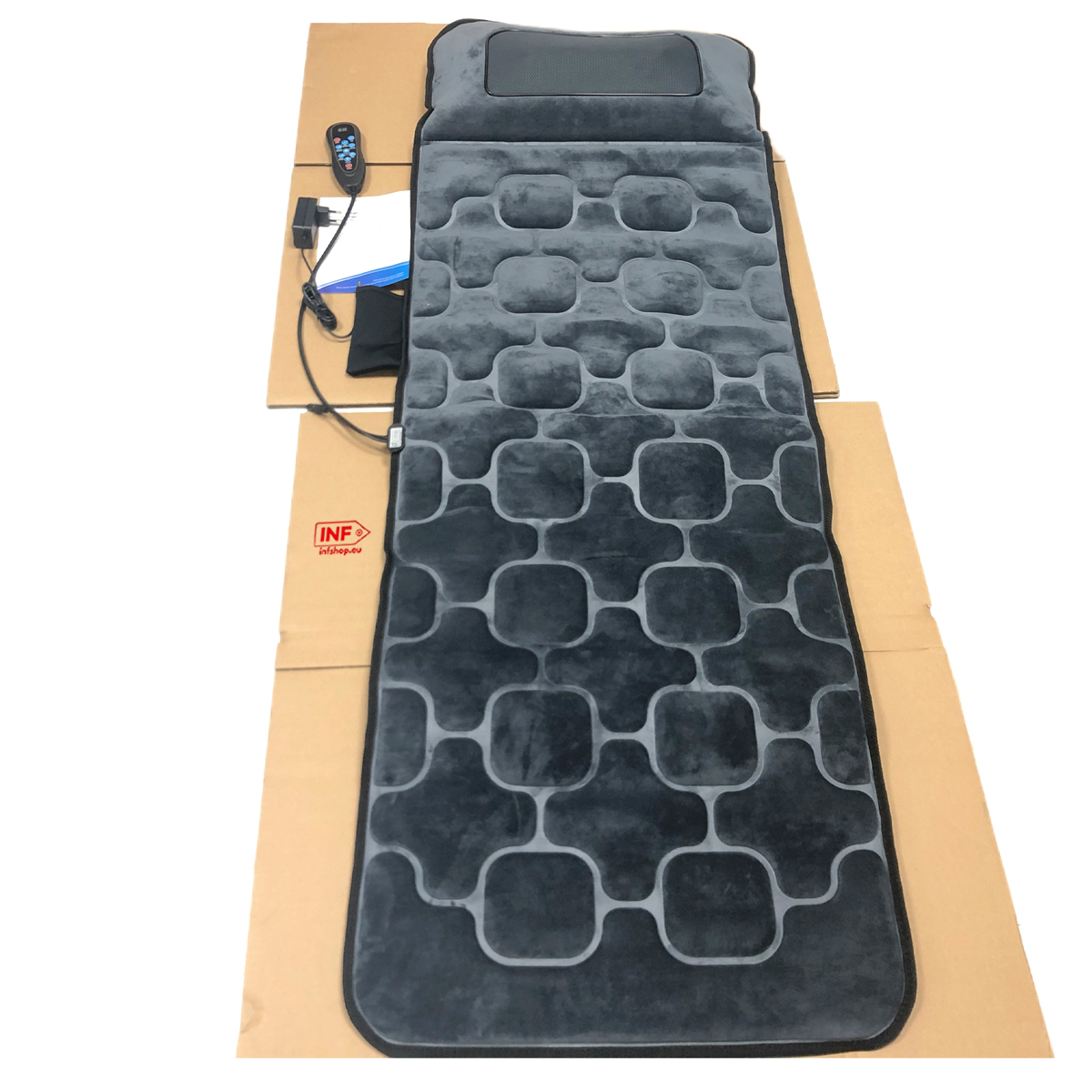 Graue Massagematte mit Fernbedienung auf Karton.