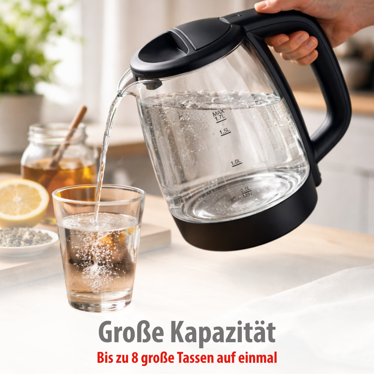 Wasser wird aus einem Wasserkocher in ein Glas gegossen. Zitrone und Honig sind zu sehen.