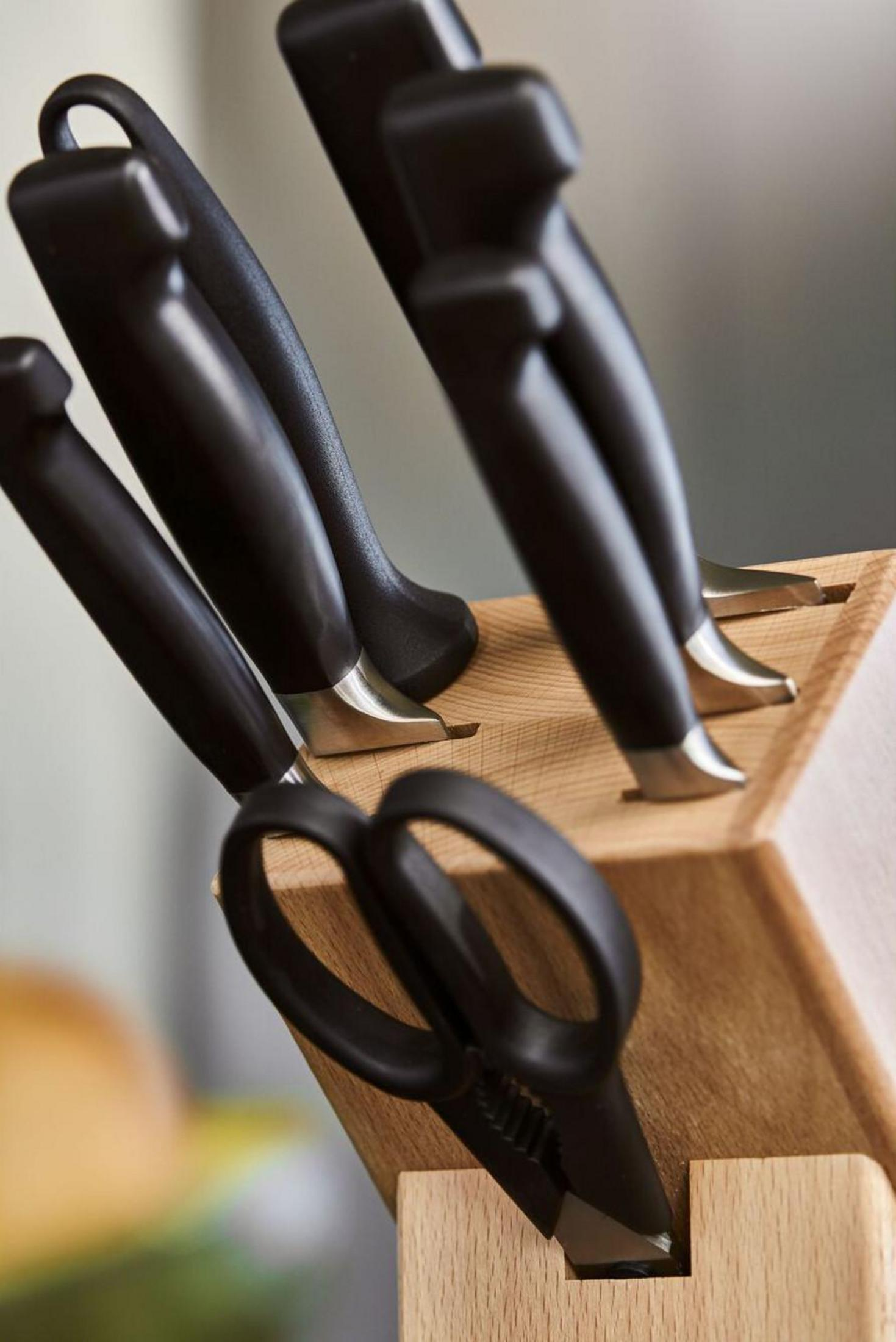 Drewniany blok z czarnymi nożami i nożyczkami.