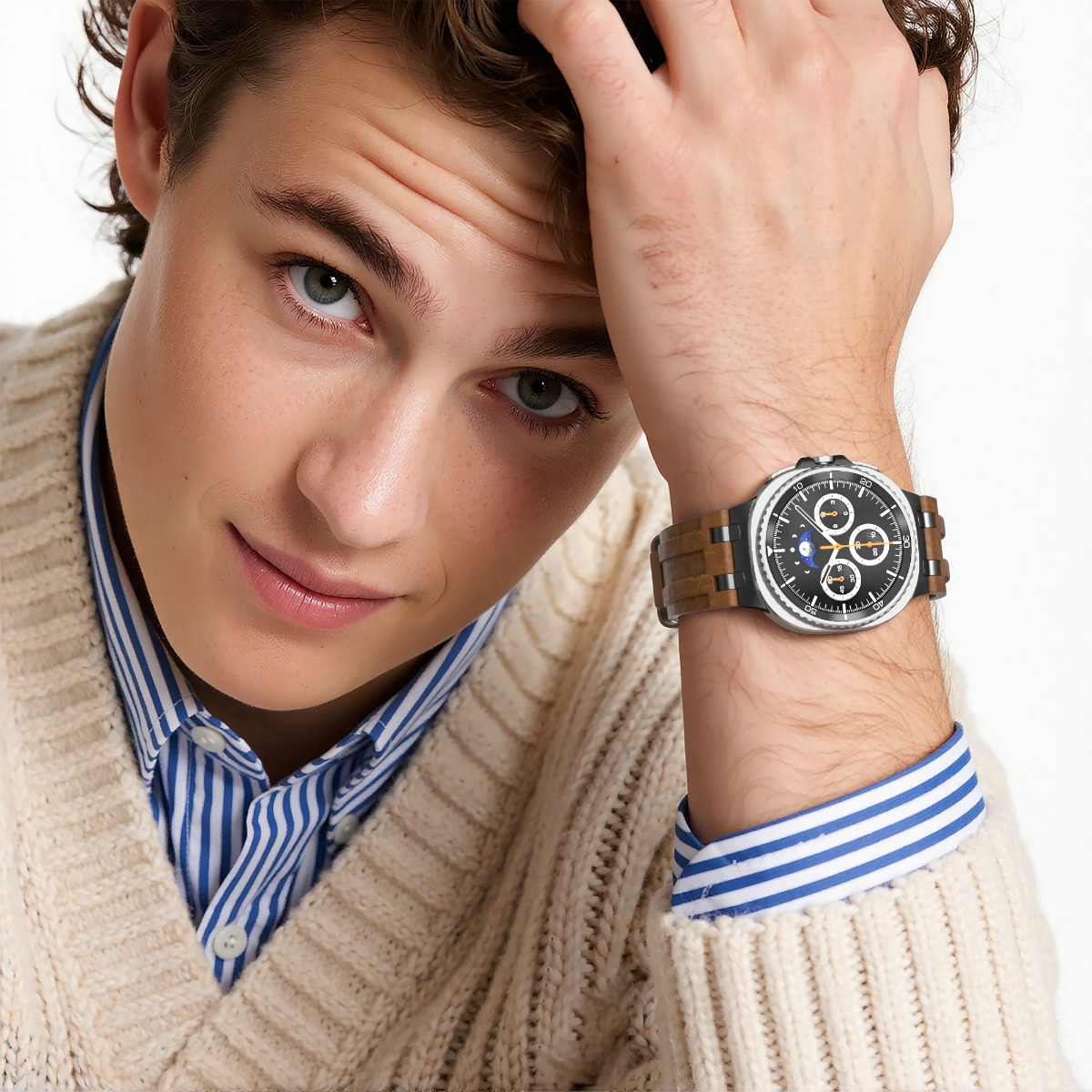 Ein junger Mann mit einer Uhr am Handgelenk, der sein Haar berührt.