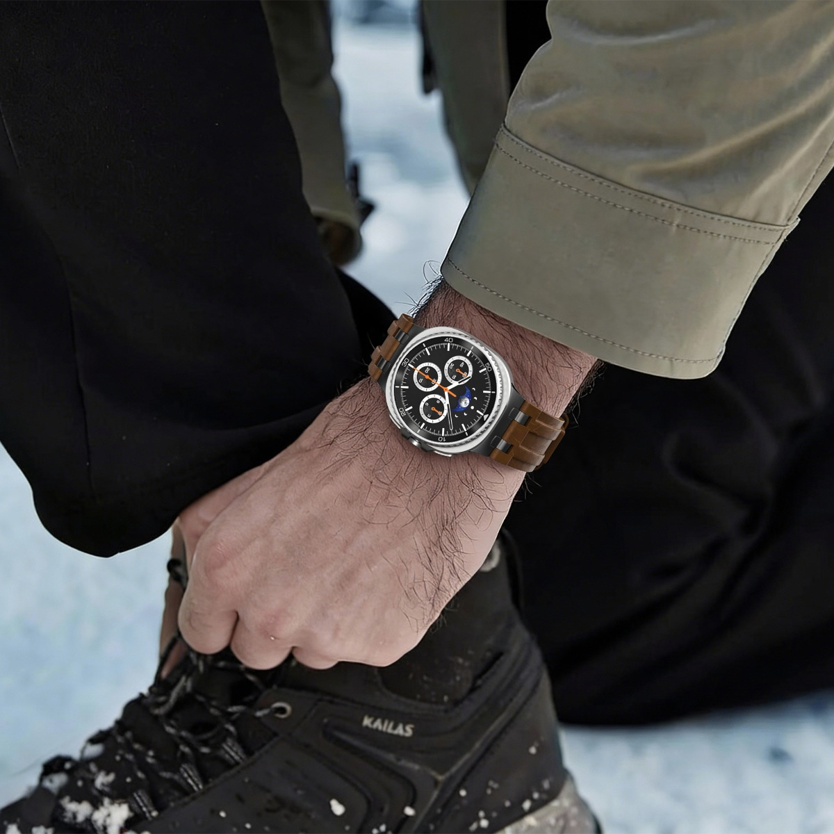 Ein Mann mit einer Uhr am Handgelenk, der auf Schnee sitzt.