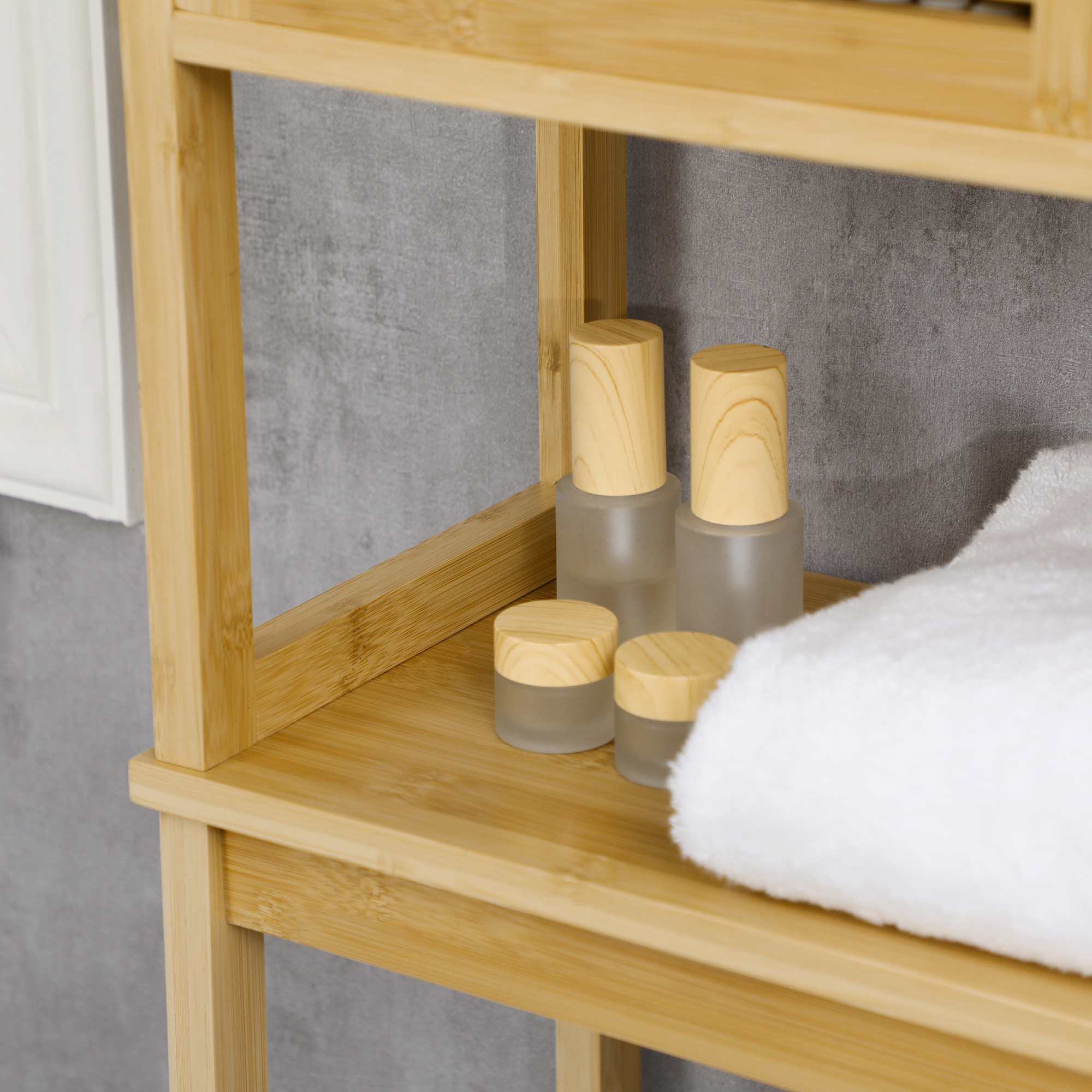 Estante de madera con recipientes cosméticos y toalla contra pared.
