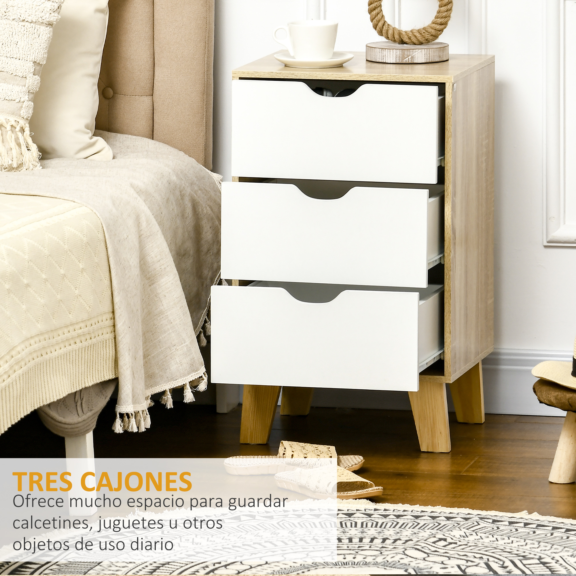 Una mesita de noche de madera clara con tres cajones blancos junto a una cama.