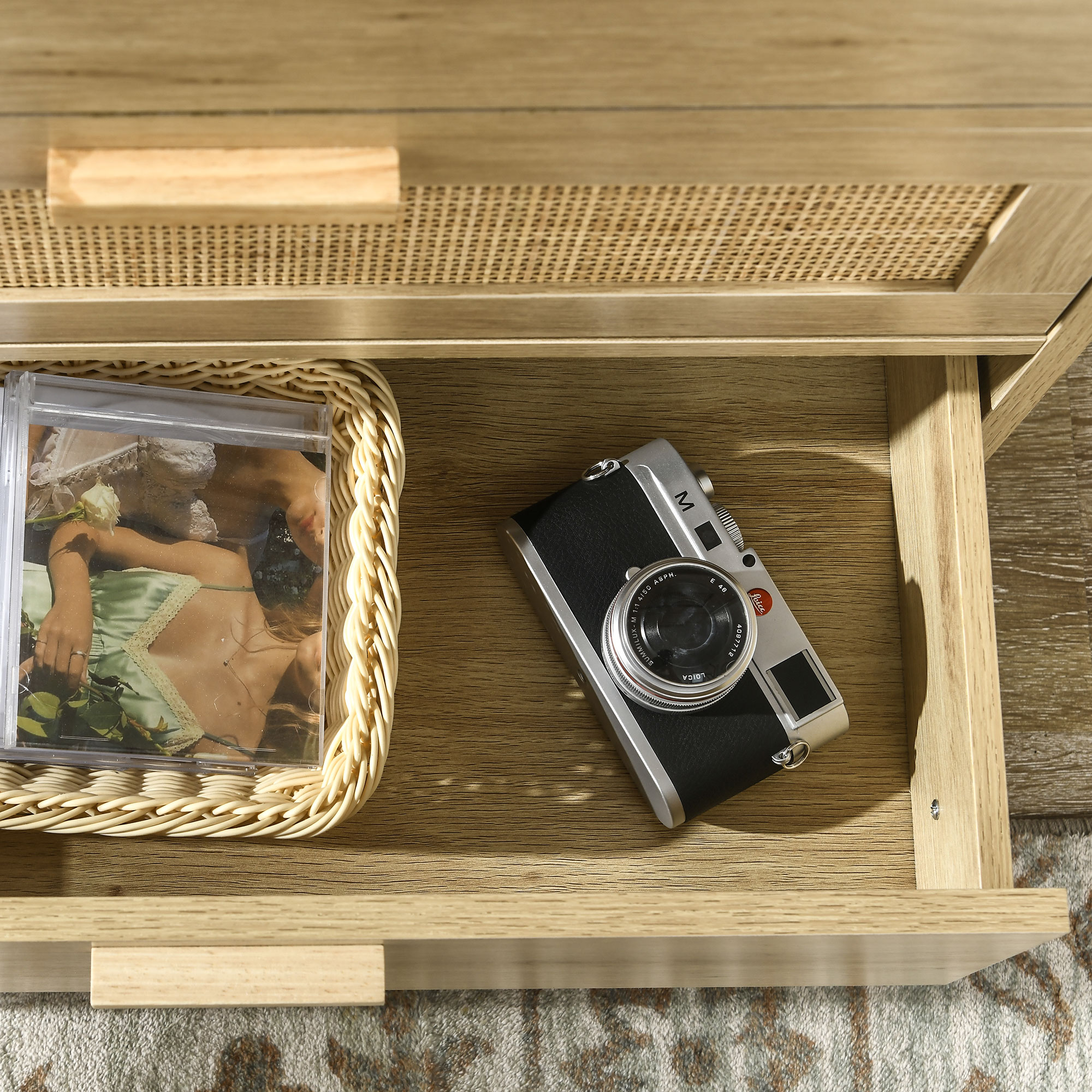 Una cámara y una funda de CD dentro de un cajón de madera.