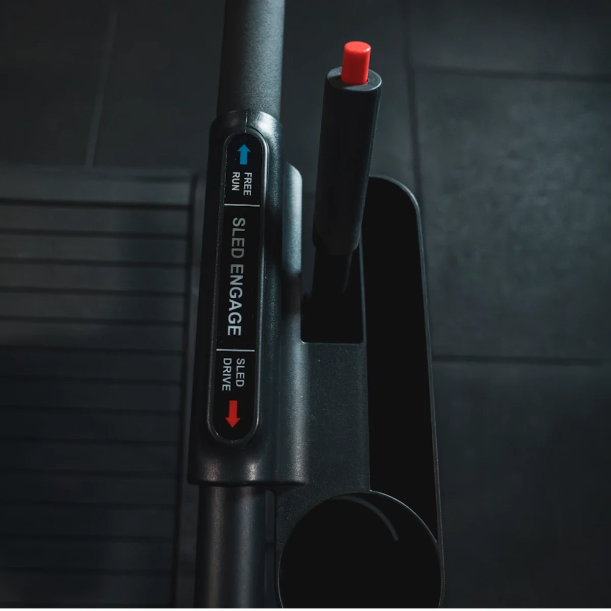 Close-up of a sled engage lever on gym equipment with labels.