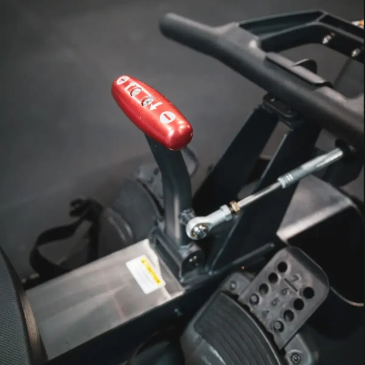 Rode bedieningshendel met cijfers en pijlen op fitnessapparaat.