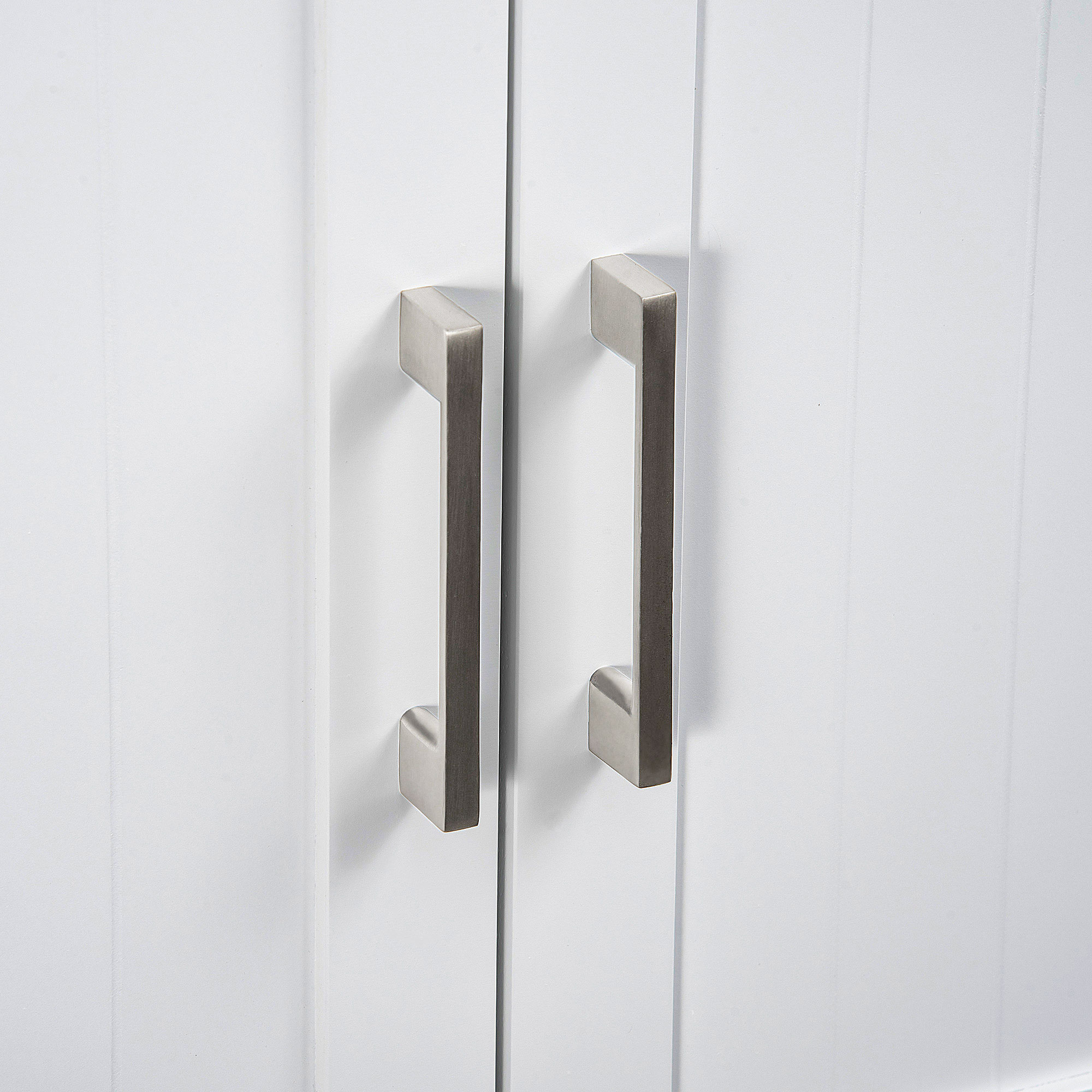 Dos tiradores plateados en una puerta blanca con líneas verticales.