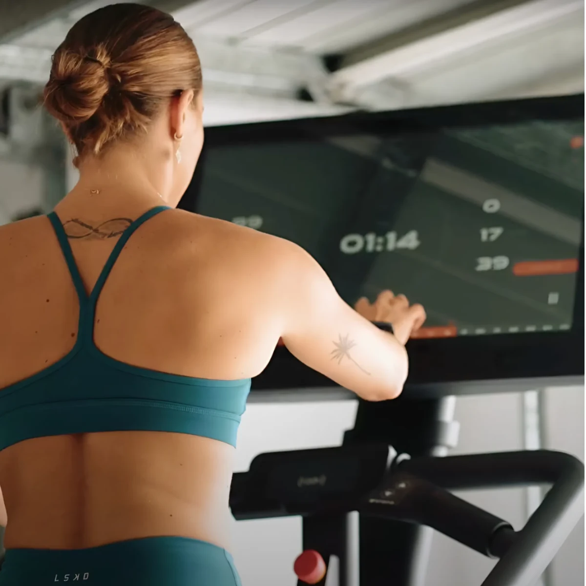 Woman exercising on a treadmill, display shows 01:14.