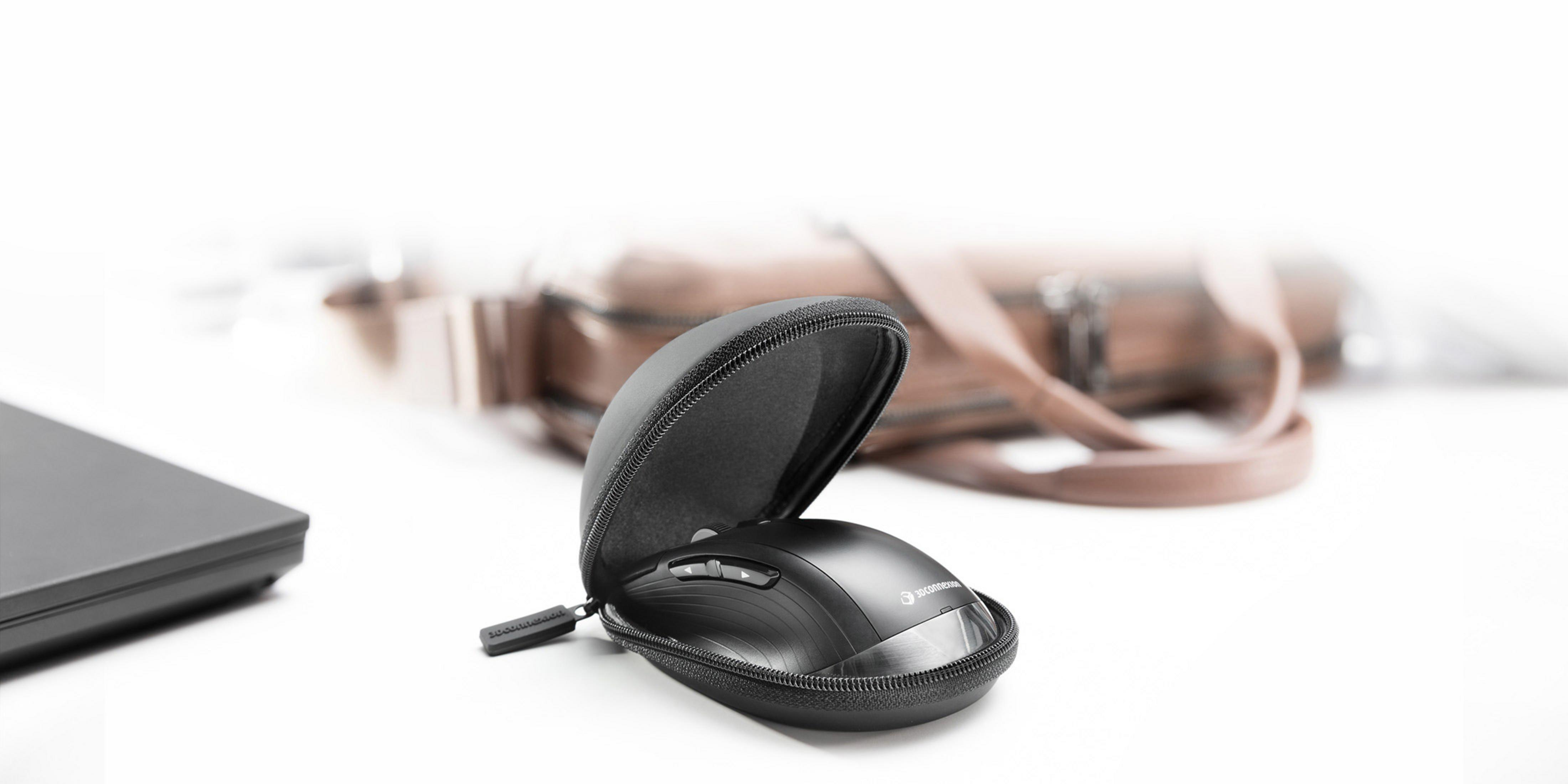 Schwarze Computermaus in schwarzer Tasche, daneben ein Laptop und eine Ledertasche.