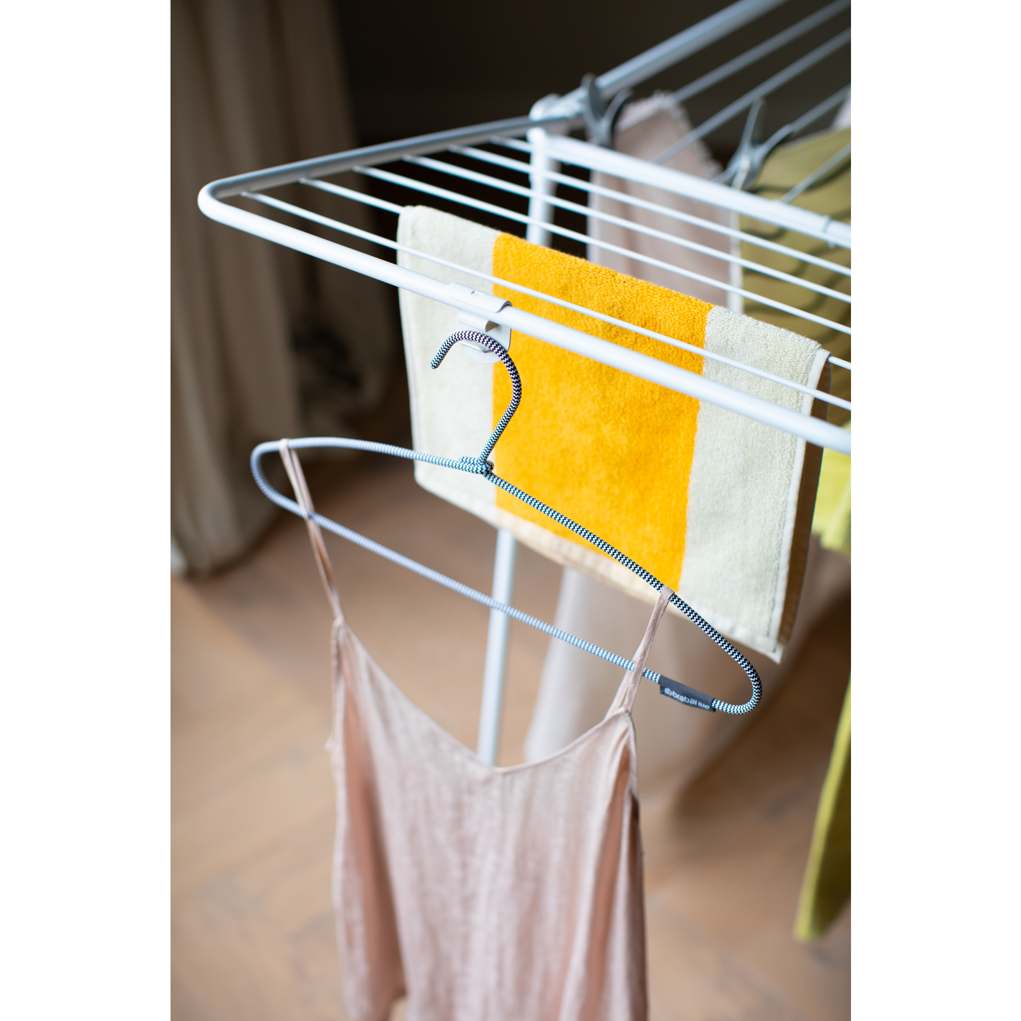 Een roze hemdje hangt aan een zwart-witte hanger op een wasrek.