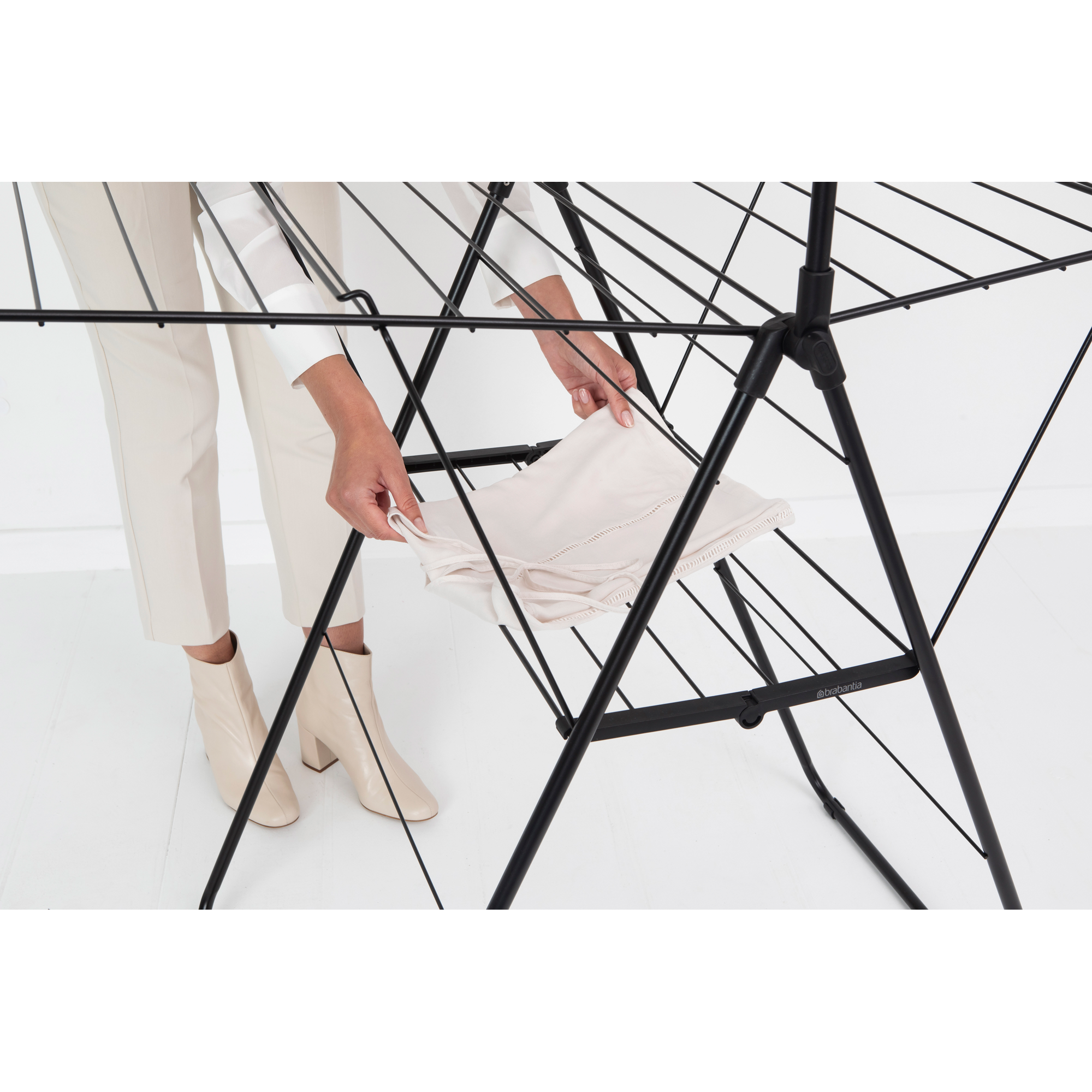A person is placing laundry on a black drying rack.