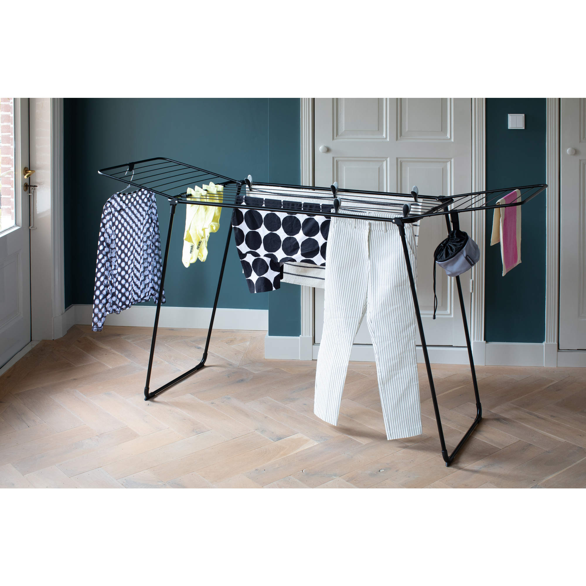 Un étendoir à linge noir avec des vêtements, y compris un pantalon rayé.