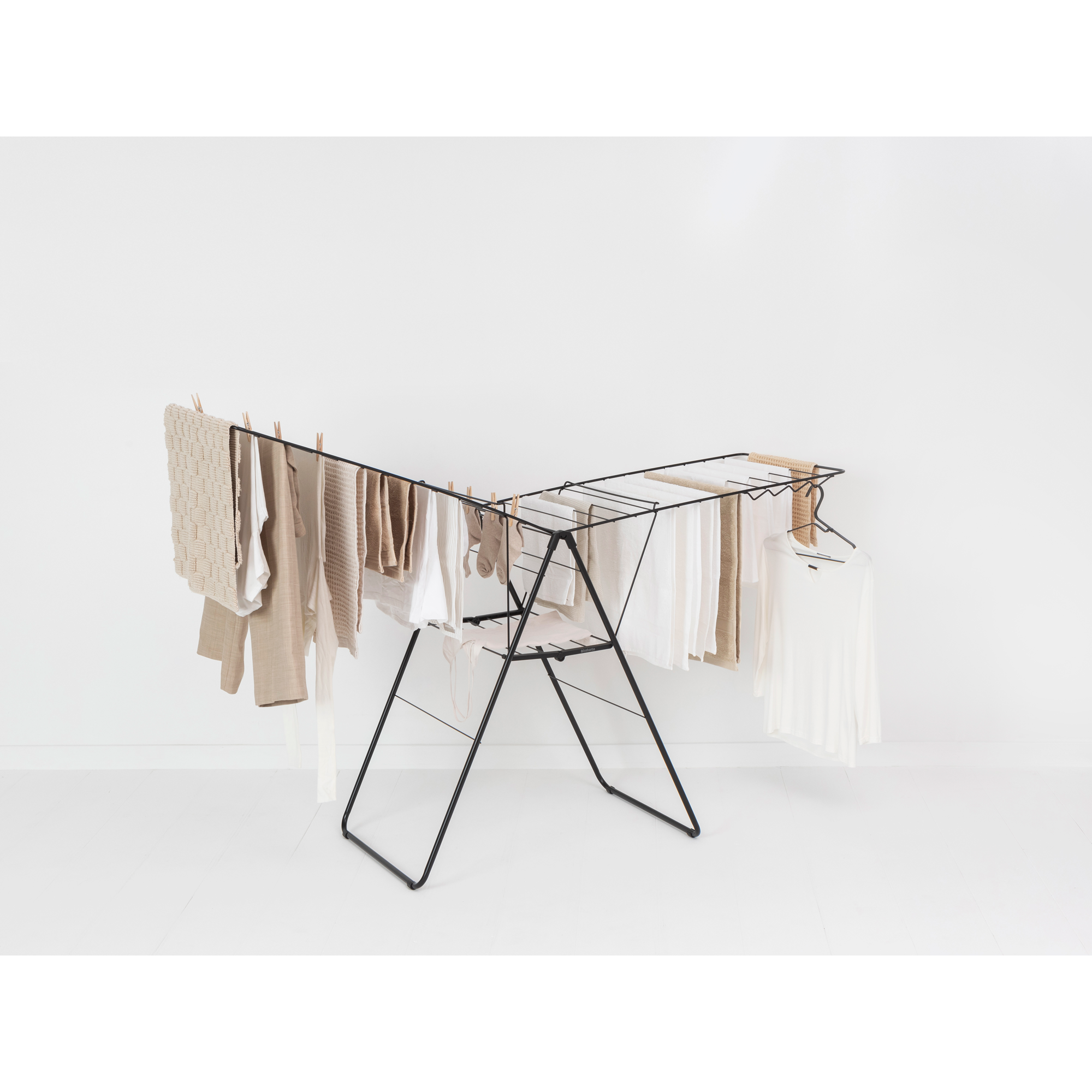 A black clothes drying rack with neutral-colored clothes.