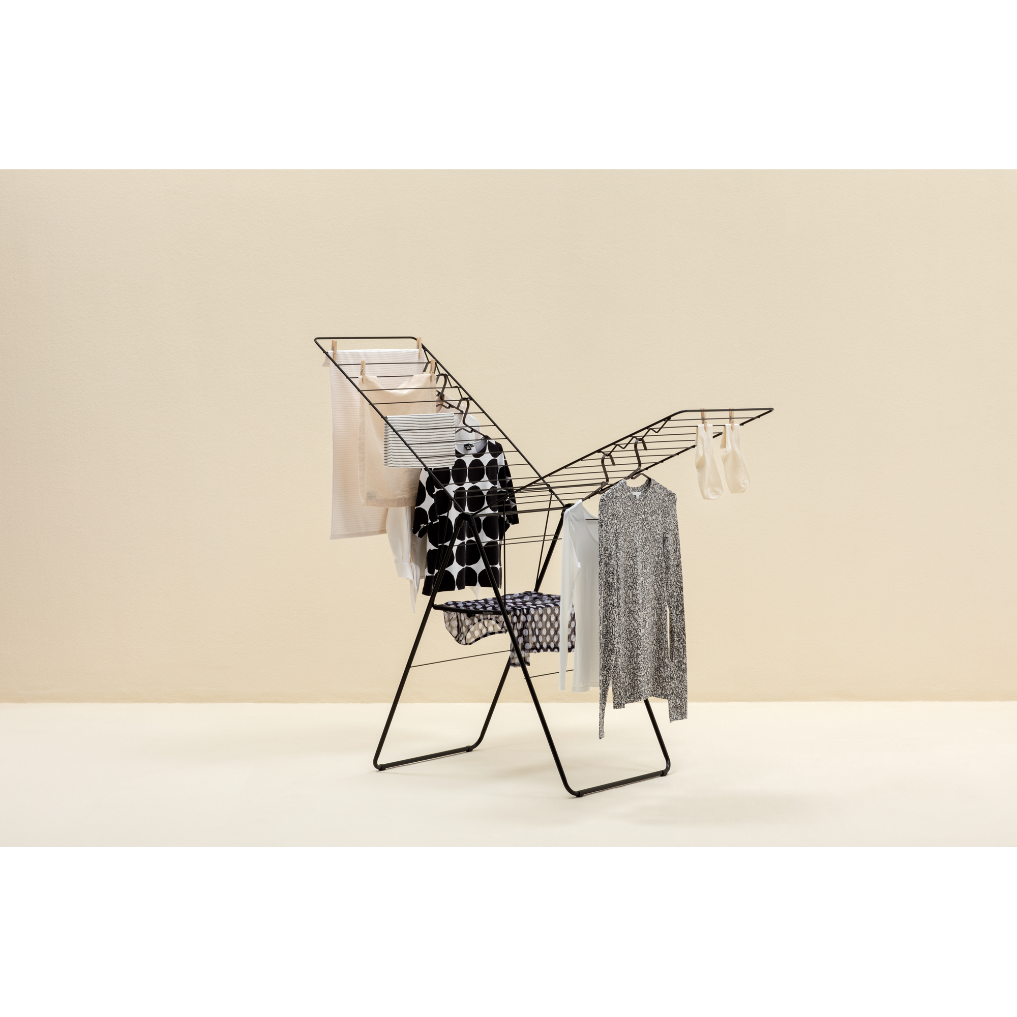 A black clothes drying rack with garments, including striped and spotted items.