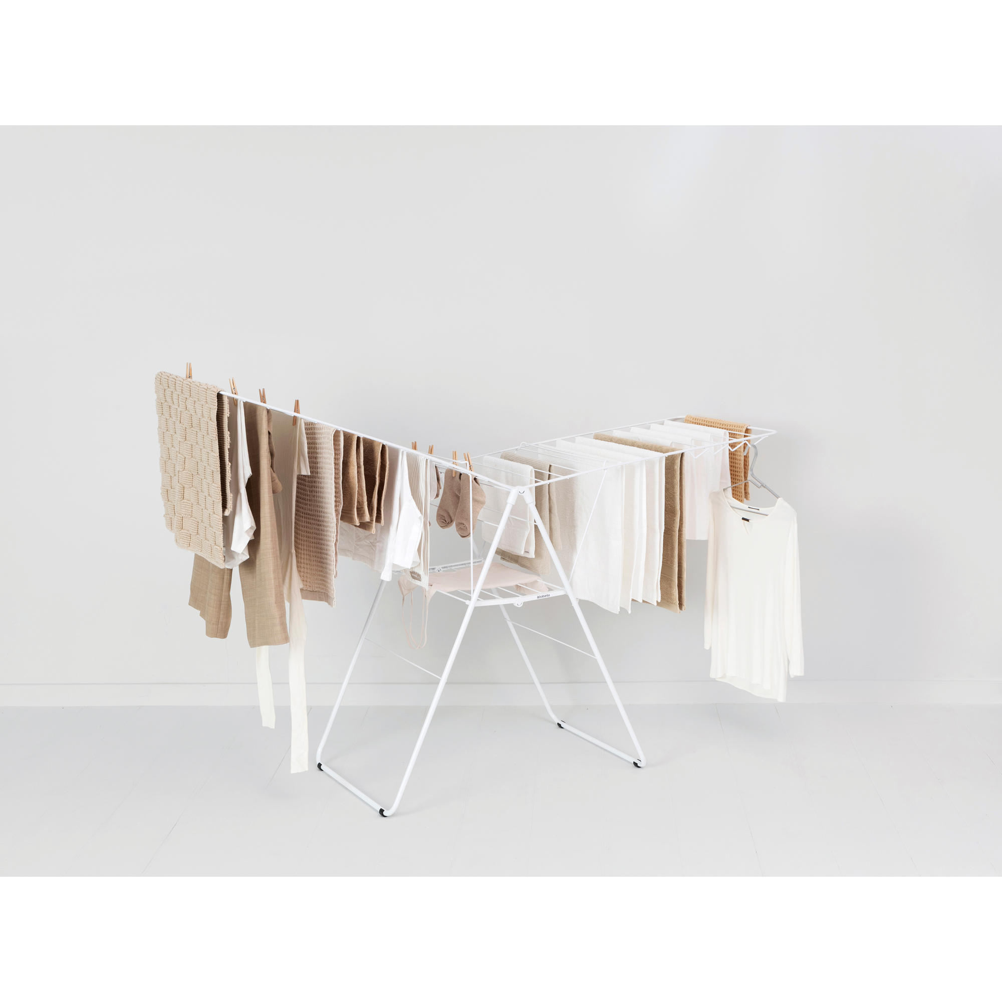 A white clothes drying rack with beige and white laundry air drying.