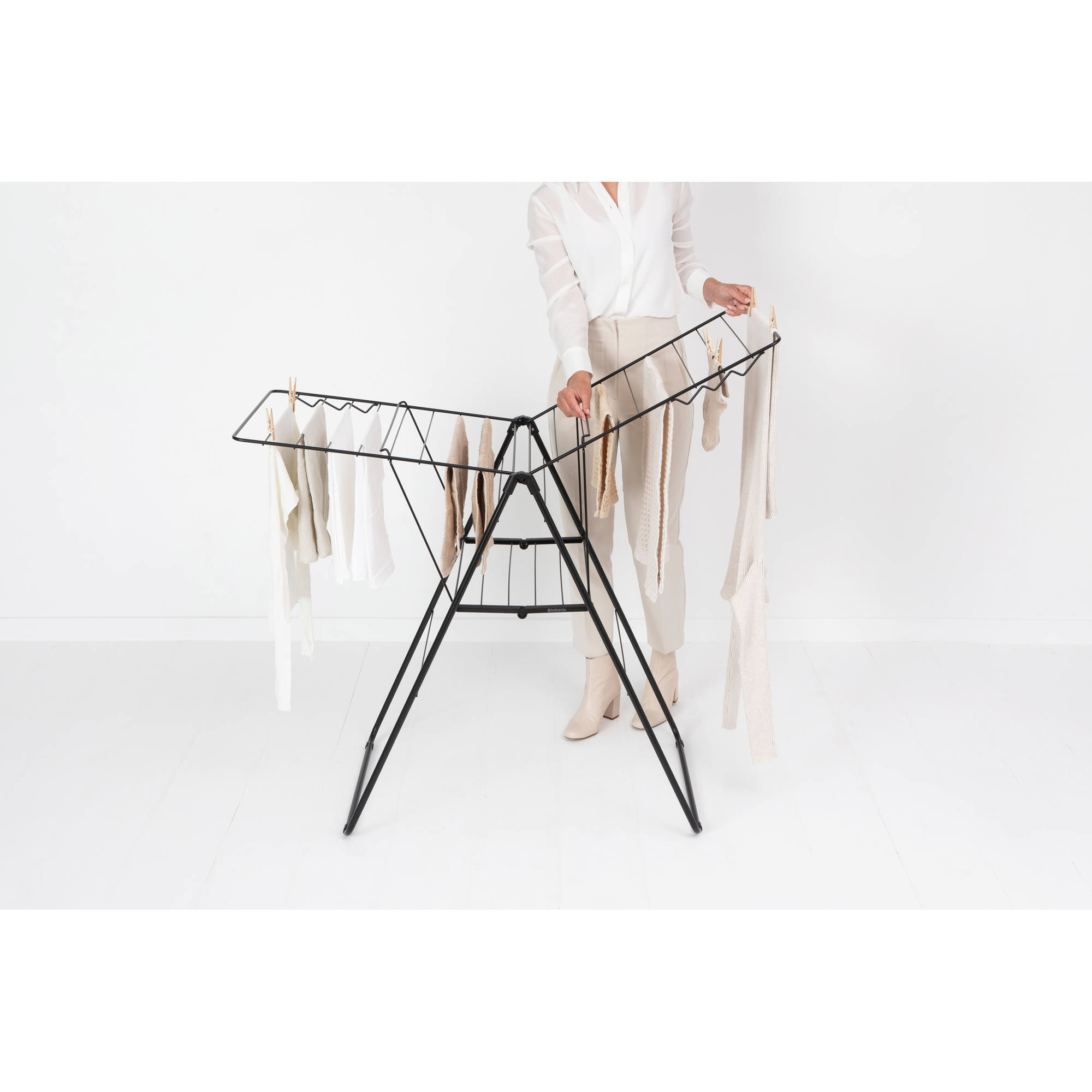 A person is hanging laundry on a black clothes drying rack.