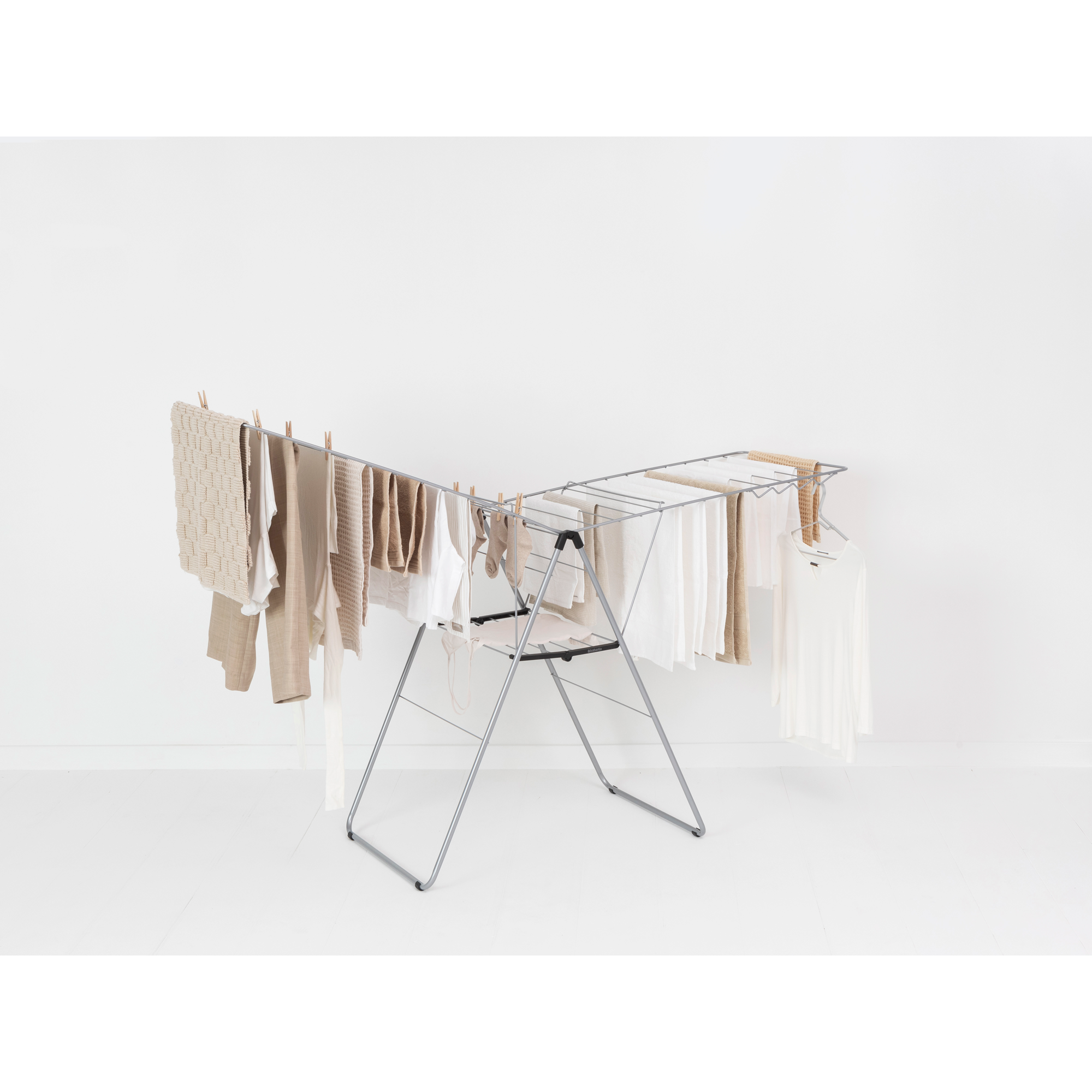 A metal drying rack with beige clothes and towels.