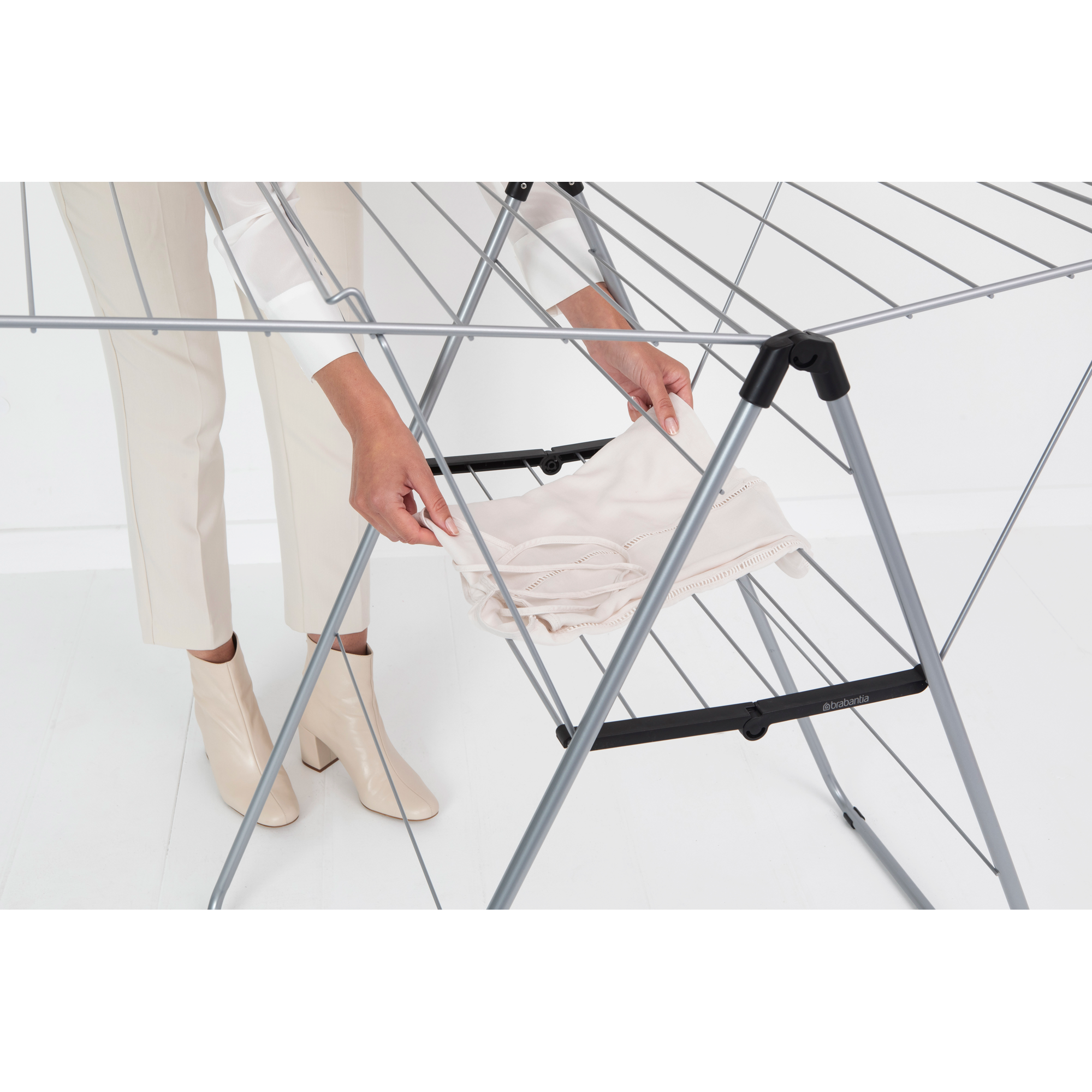A woman places a light-colored garment on a drying rack.