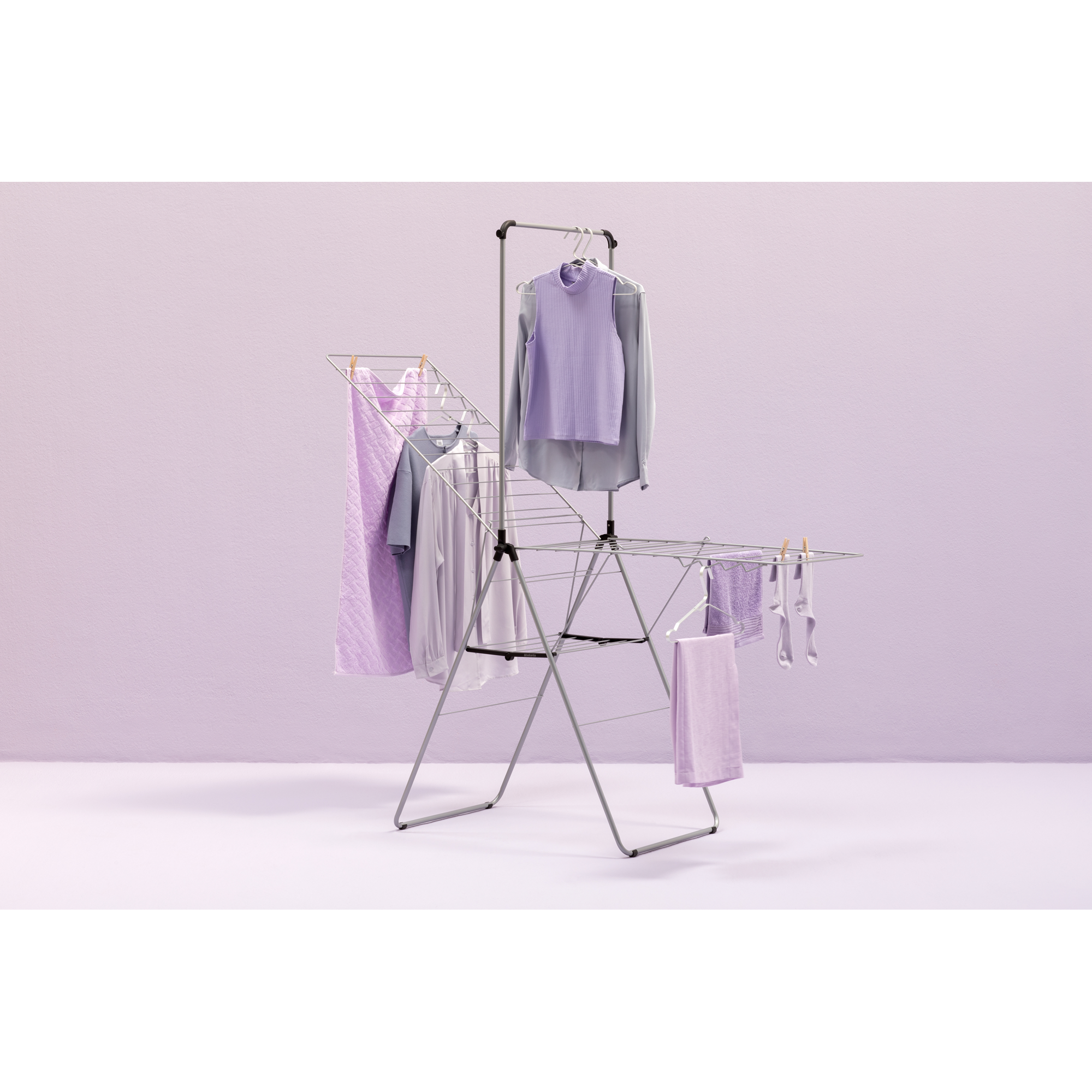 A drying rack with purple clothes and towels against a light purple background.