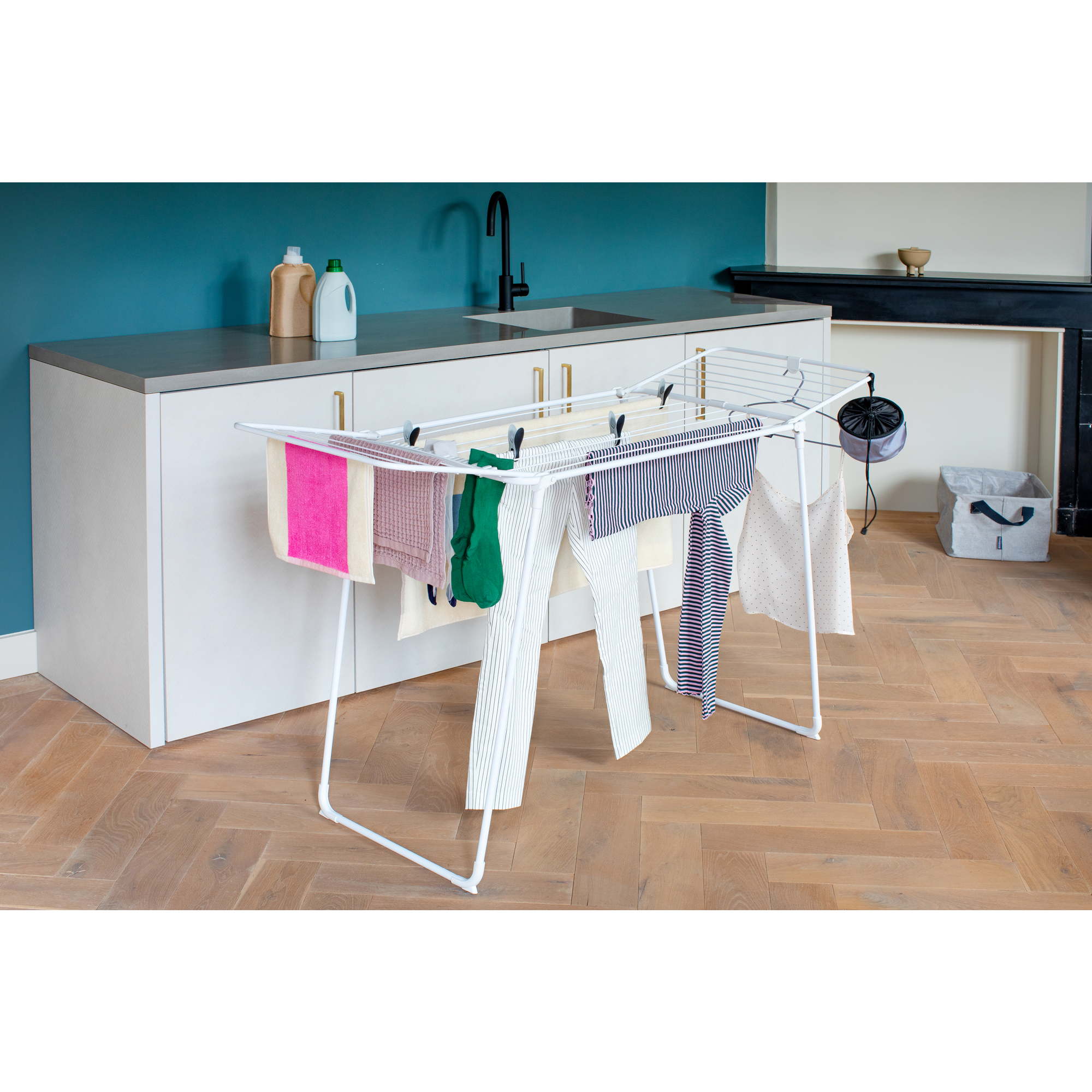 A white drying rack with colorful clothes, in a modern laundry room.