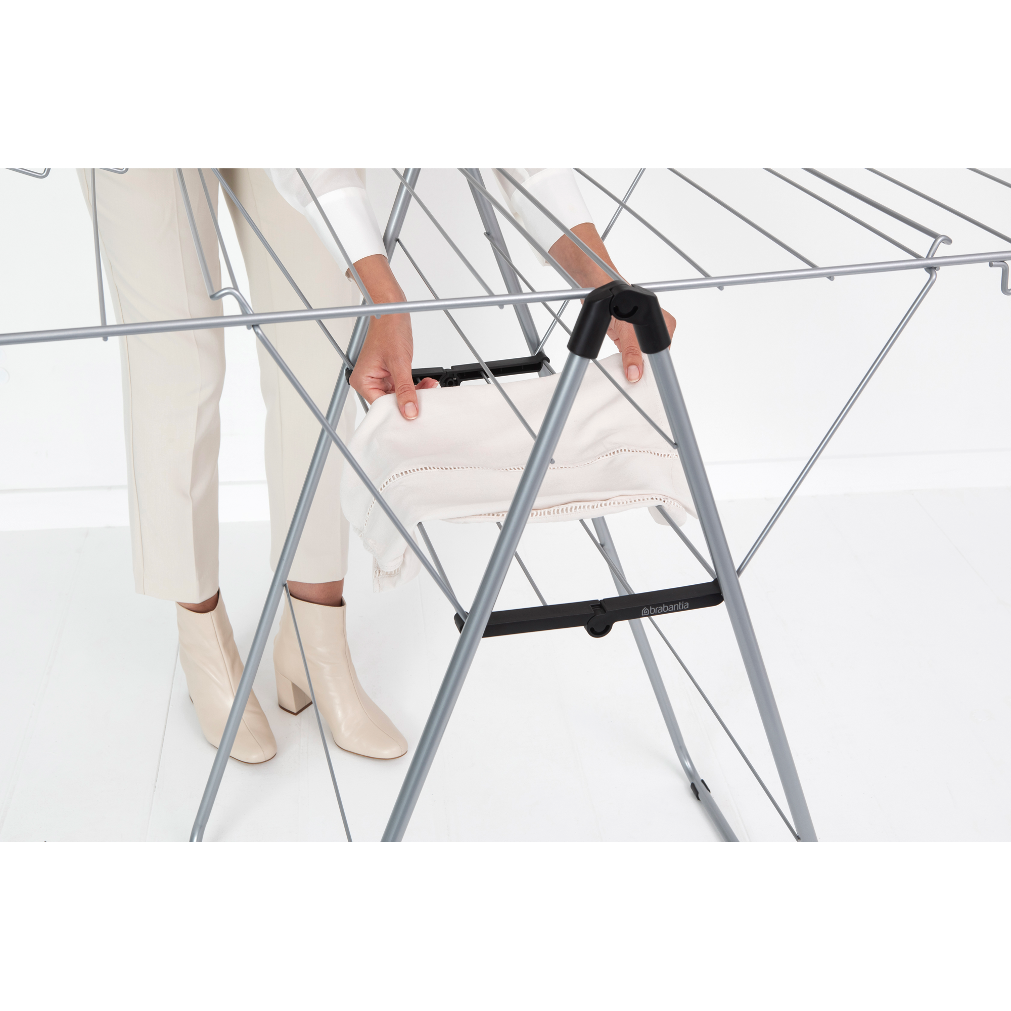 A person places a white cloth onto a drying rack.