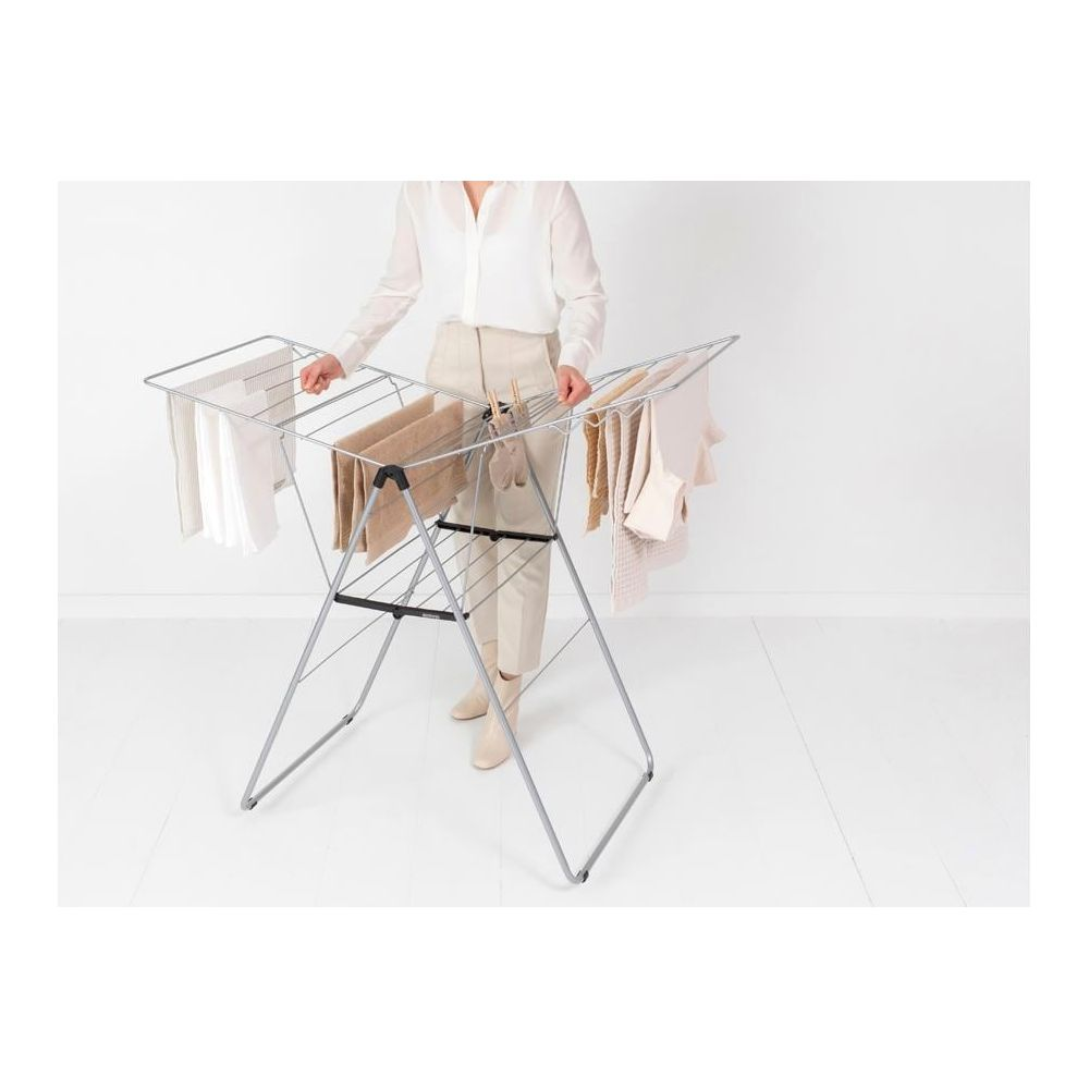 Person hangs laundry on a silver drying rack.