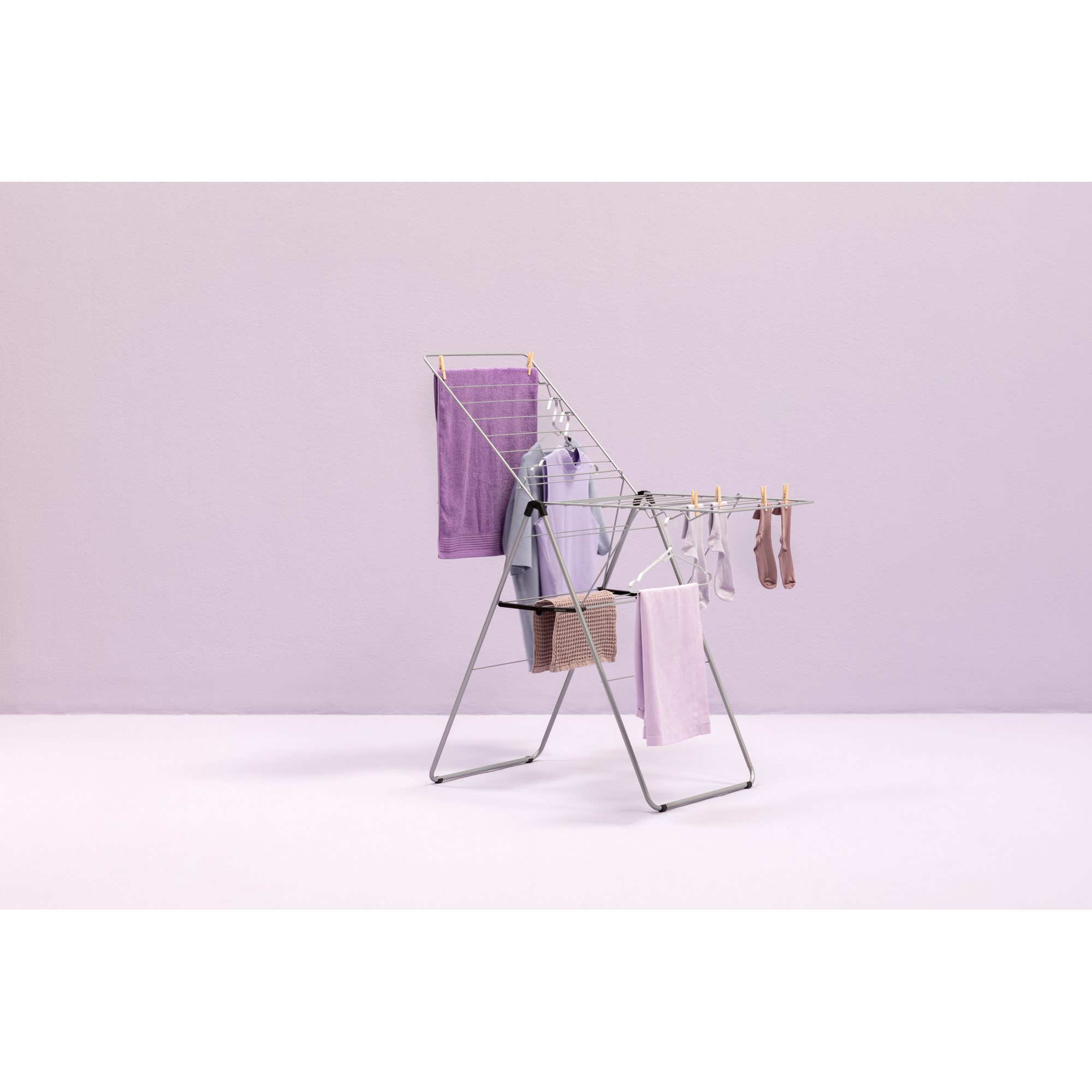 A clothes drying rack with purple clothes and towels.