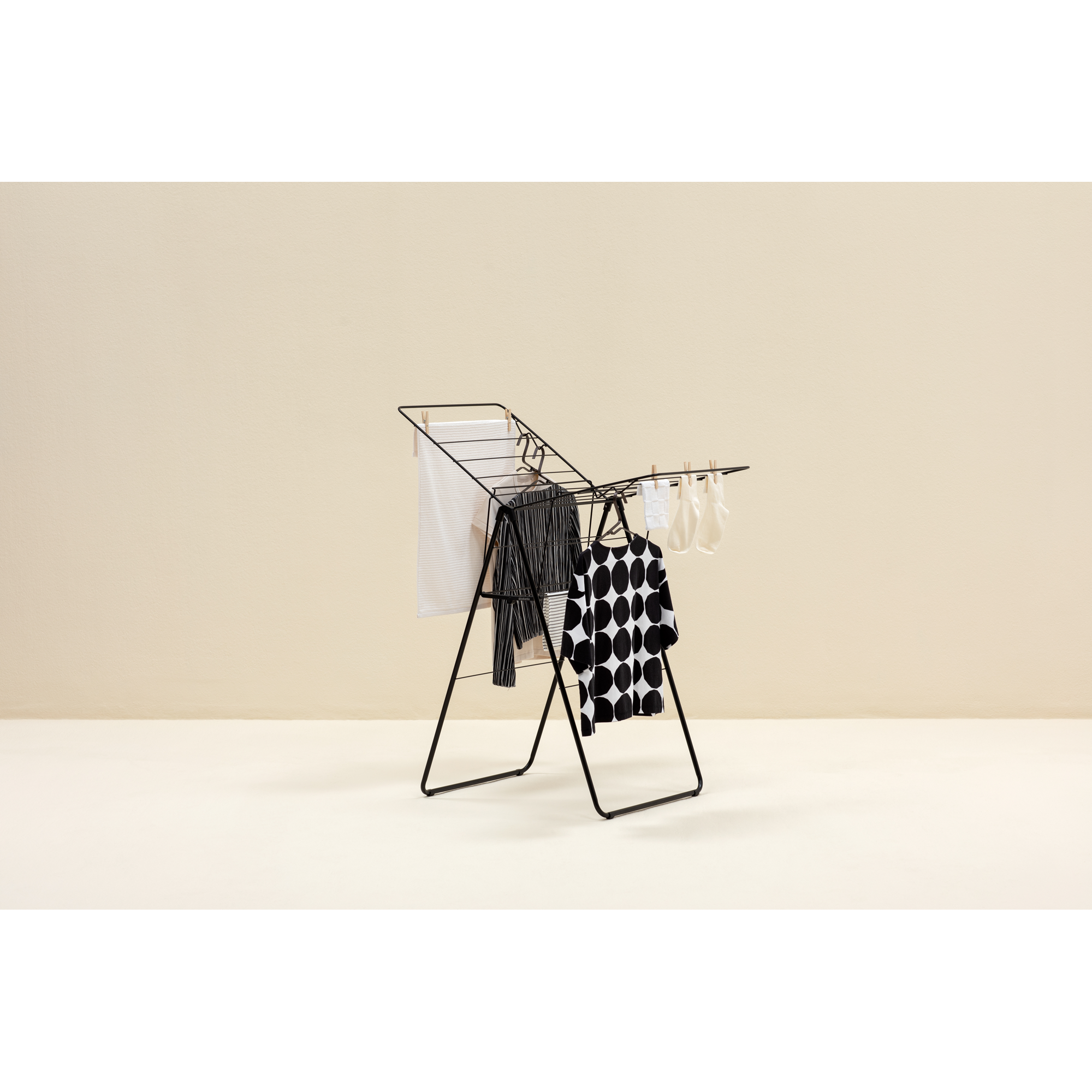 A black metal drying rack holds striped and polka dot clothes. White socks hang.