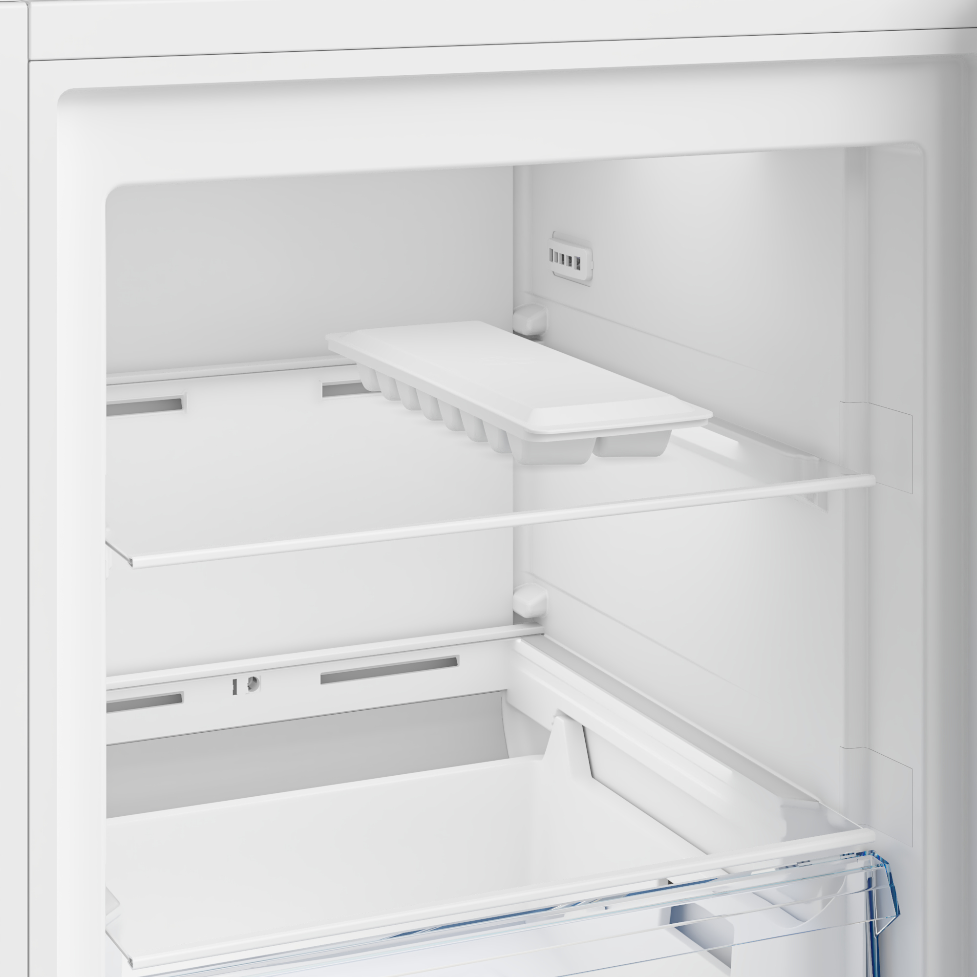 An empty refrigerator compartment with an ice cube tray and shelves.