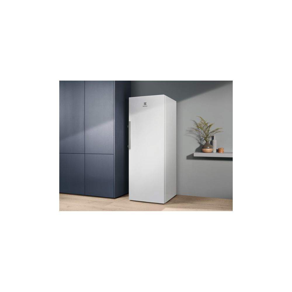 Un réfrig érateur blanc à côté d'une armoire sombre.