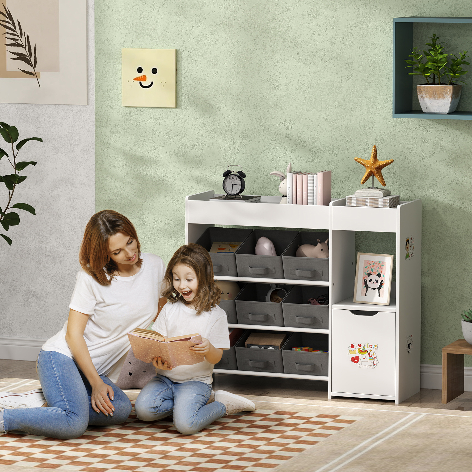 Madre e hija leen libro en el suelo. Estante blanco con juguetes y libros. Pared verde.