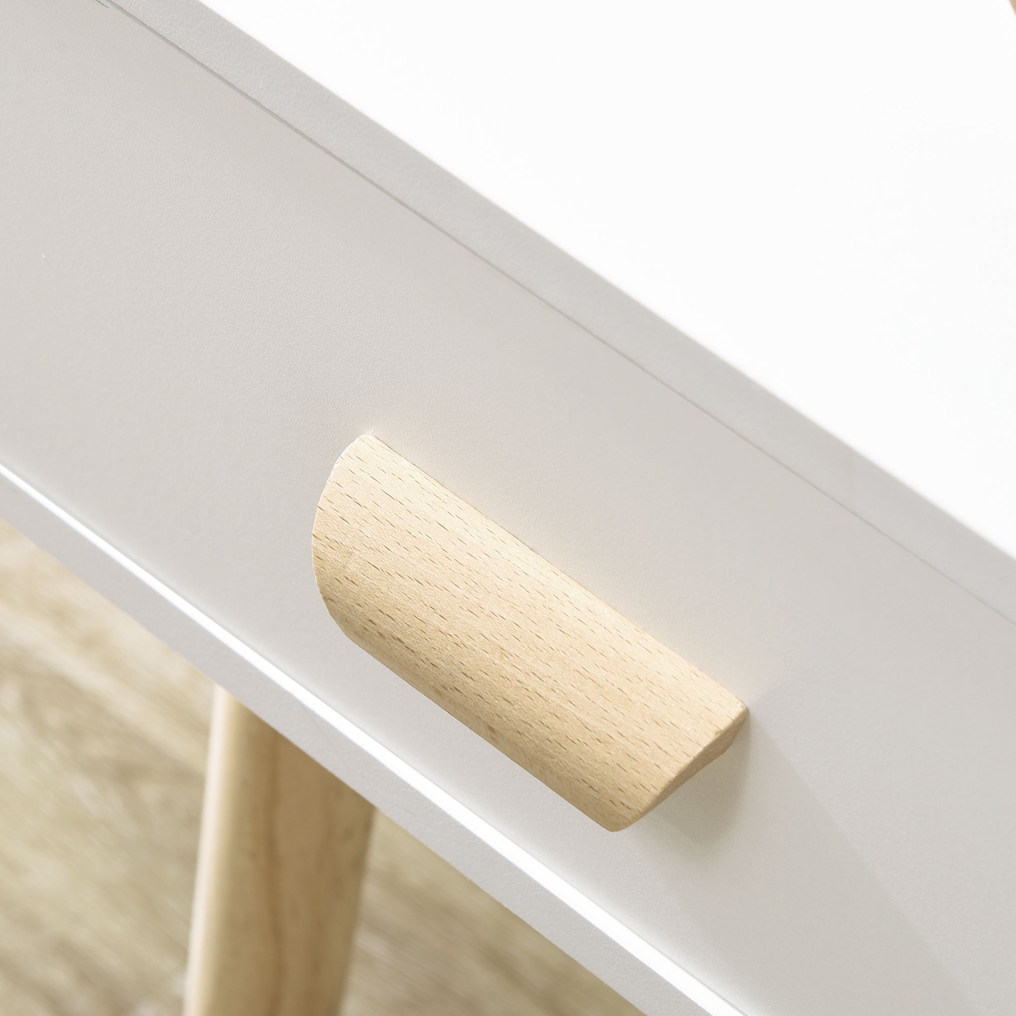 Un cajón blanco con un tirador de madera. Suelo de madera al fondo.