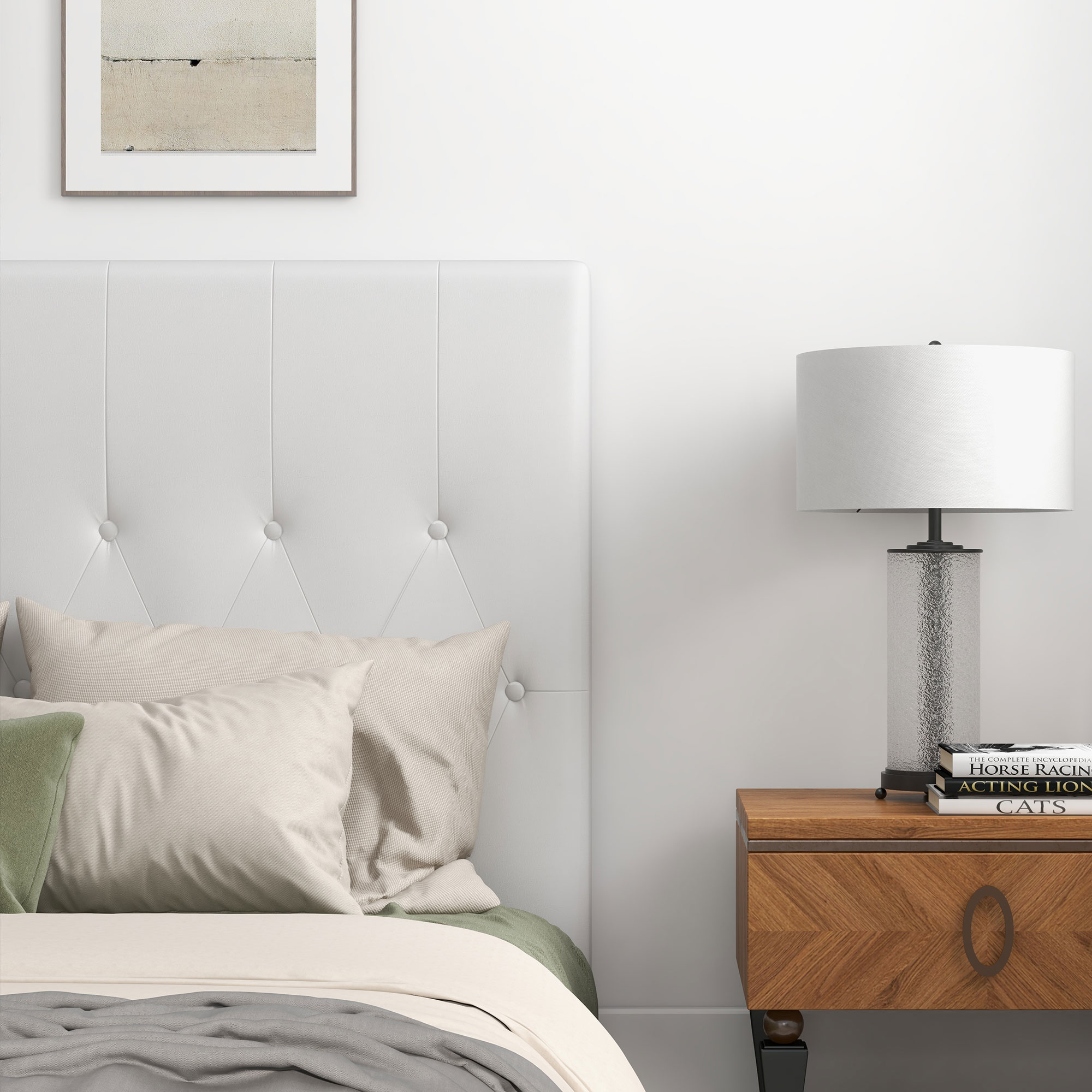 Una cama blanca con almohadas y una lámpara en una mesita de noche.