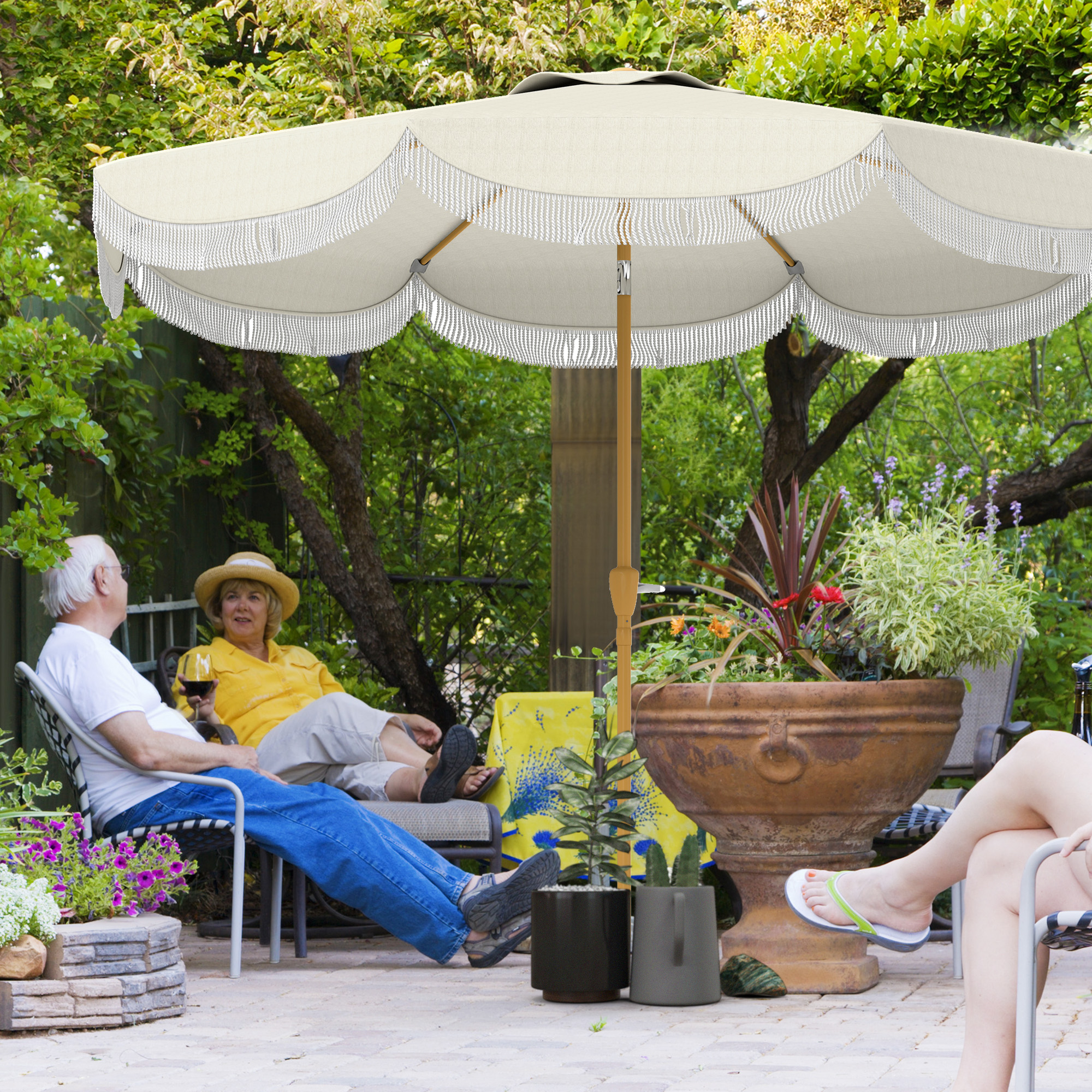Coppia rilassante sotto ombrellone in giardino. Donna beve vino.