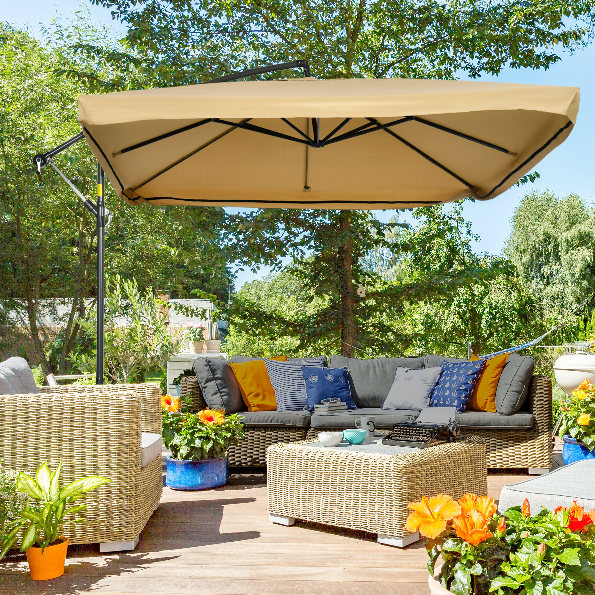 Área de patio cubierta con muebles de ratán, cojines, flores y un gran paraguas.