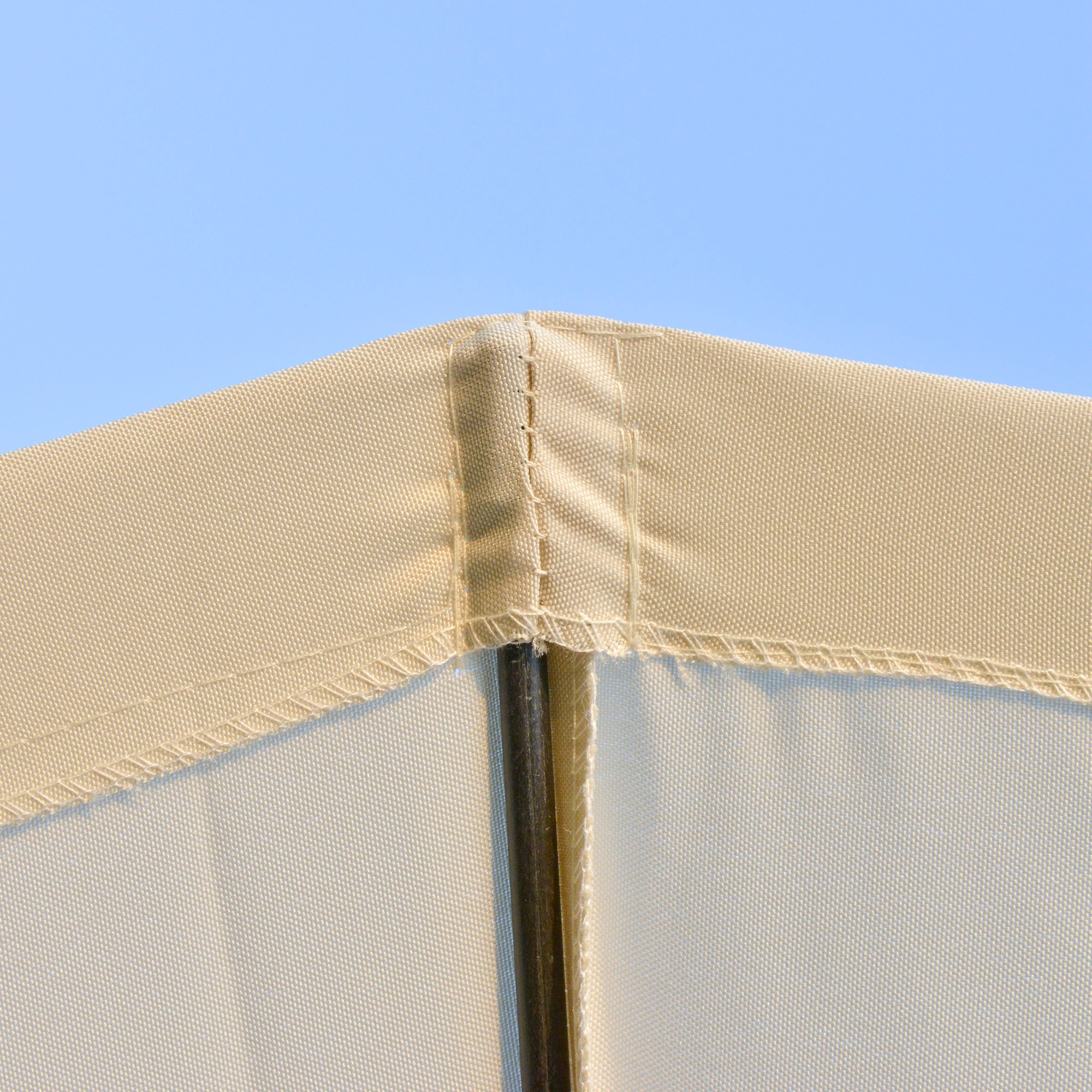 Tessuto beige con cuciture e un palo scuro contro cielo blu.