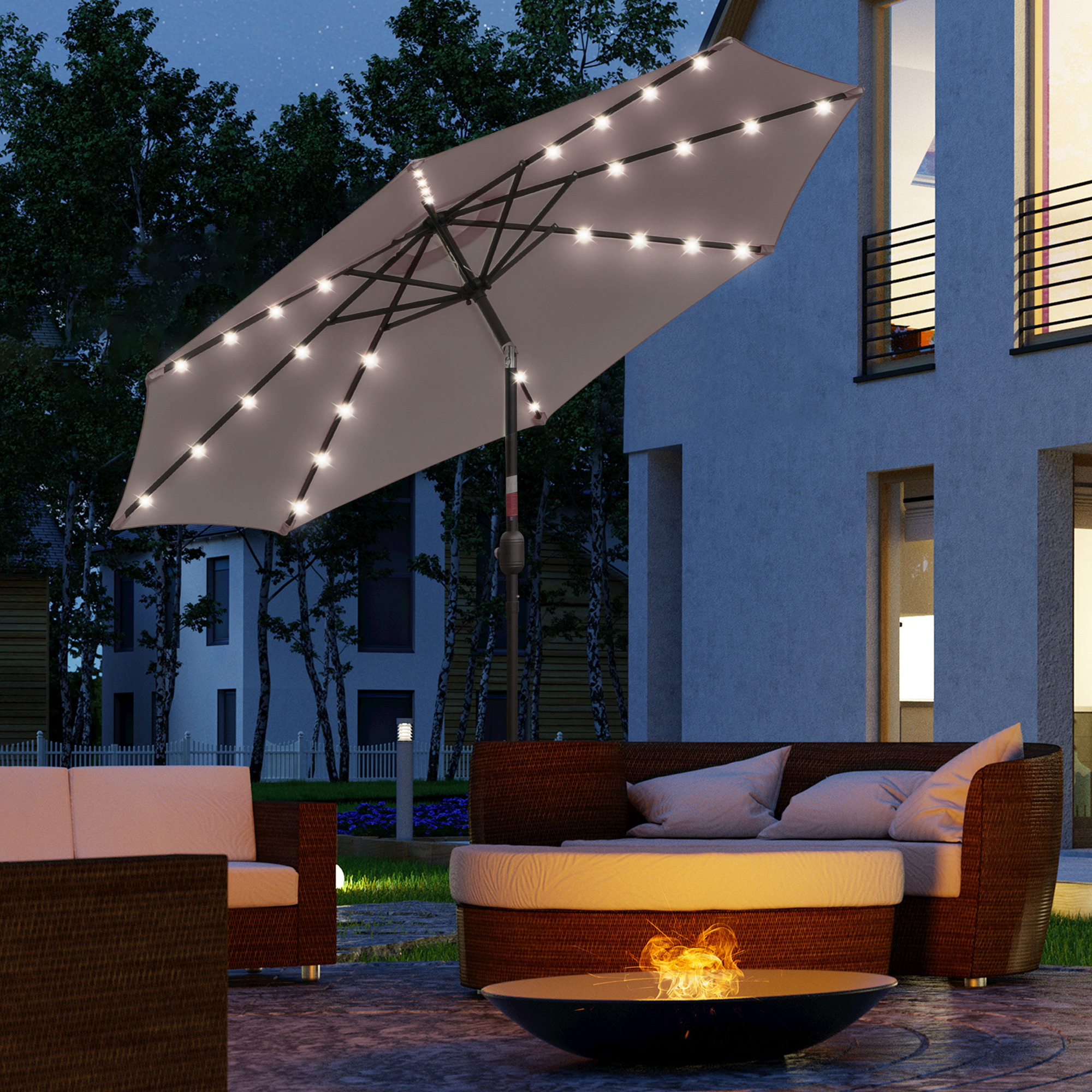 Un parasol iluminado sobre muebles de exterior junto a una hoguera por la noche.