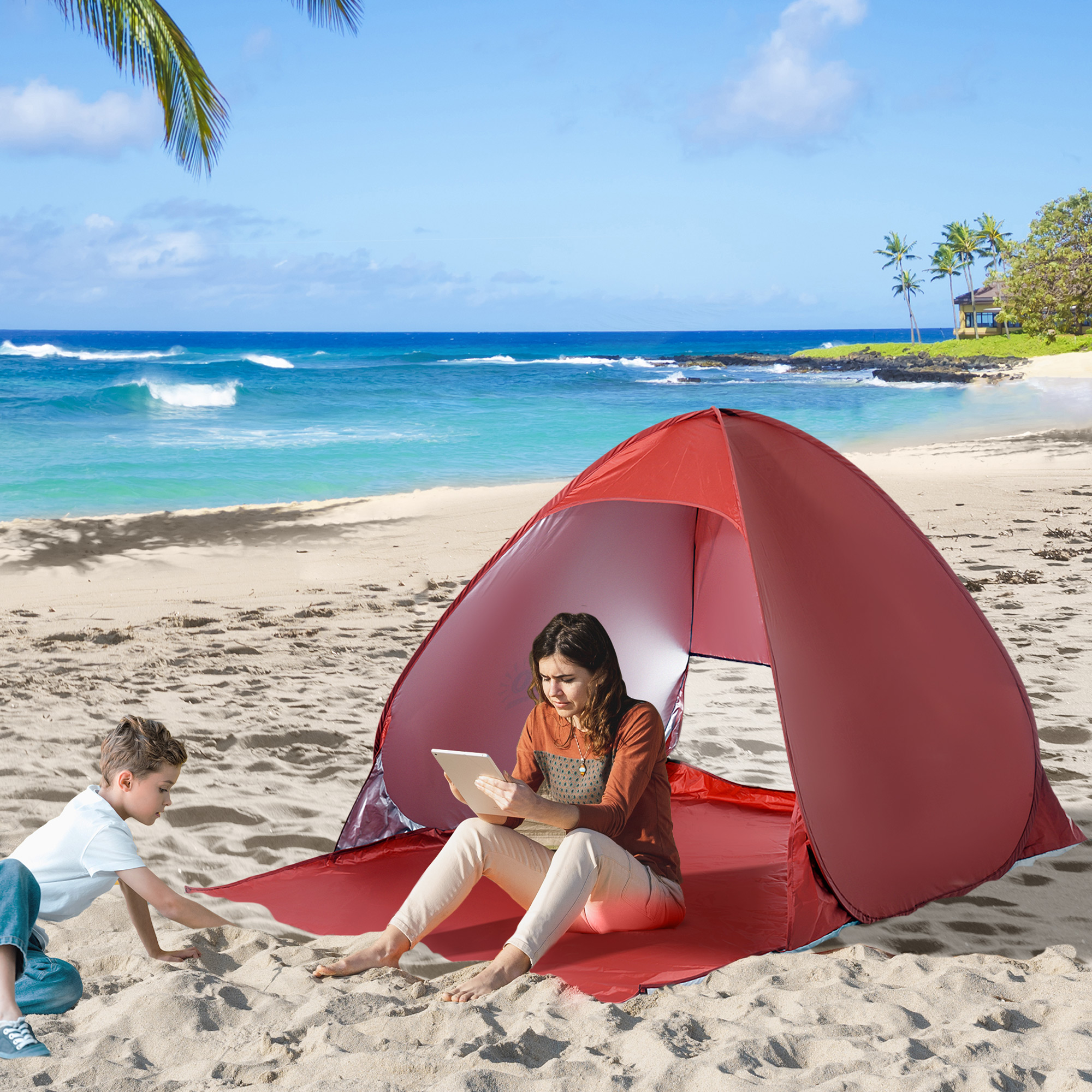 Un niño juega en la arena cerca de una carpa de playa roja, mientras una mujer usa una tablet adentro.