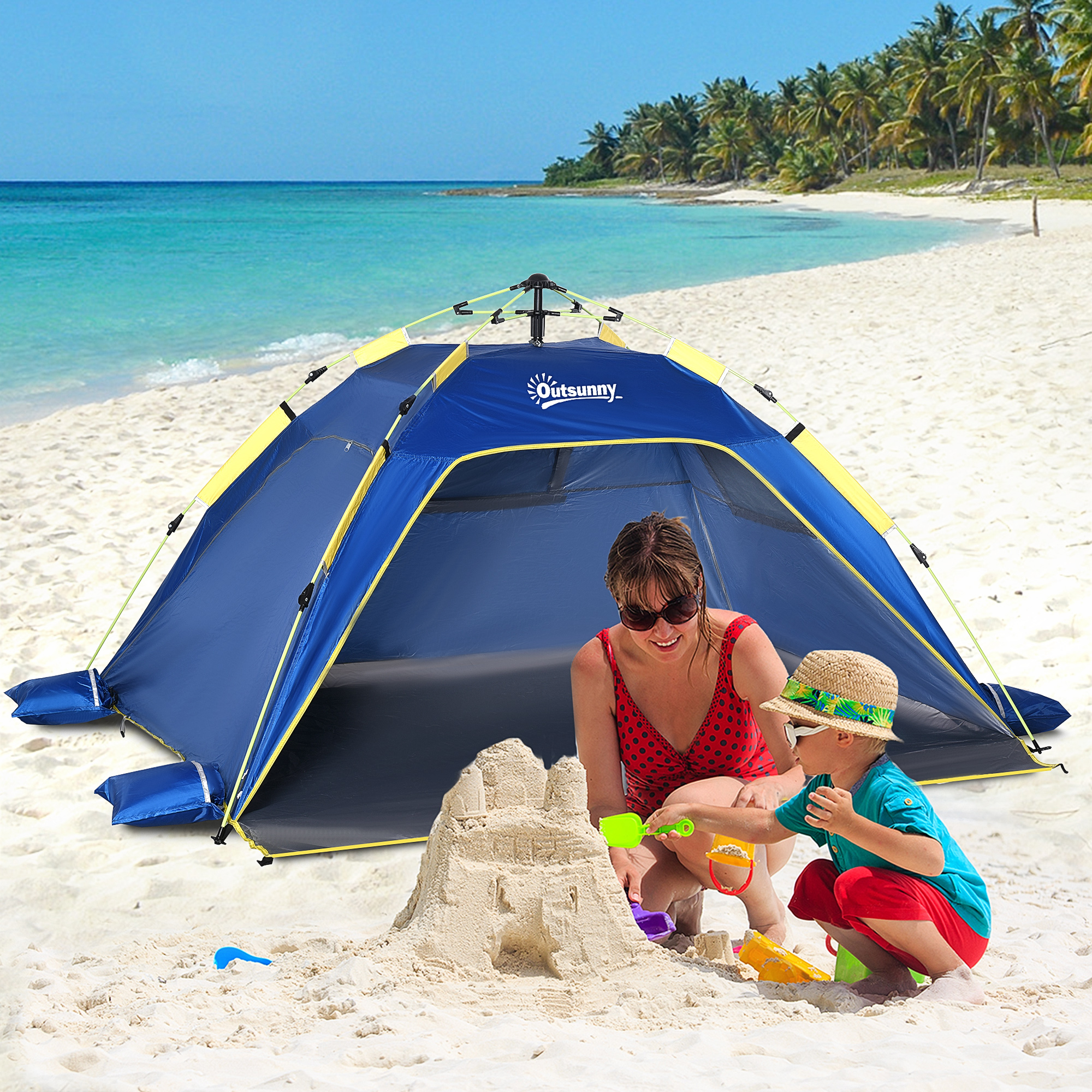 Mujer y niño construyen castillo de arena en la playa con carpa azul.