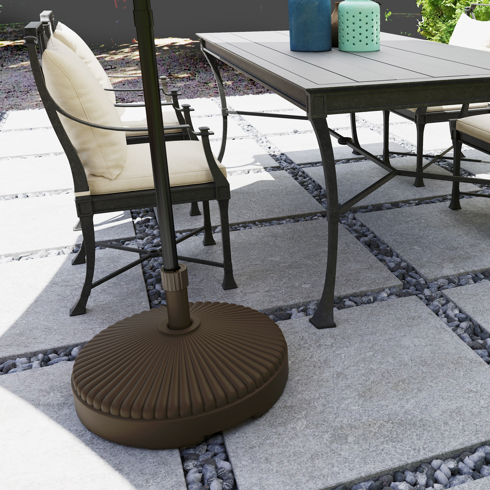 Mesa de exterior con sillas sobre losas de piedra y grava. Base de sombrilla delante.