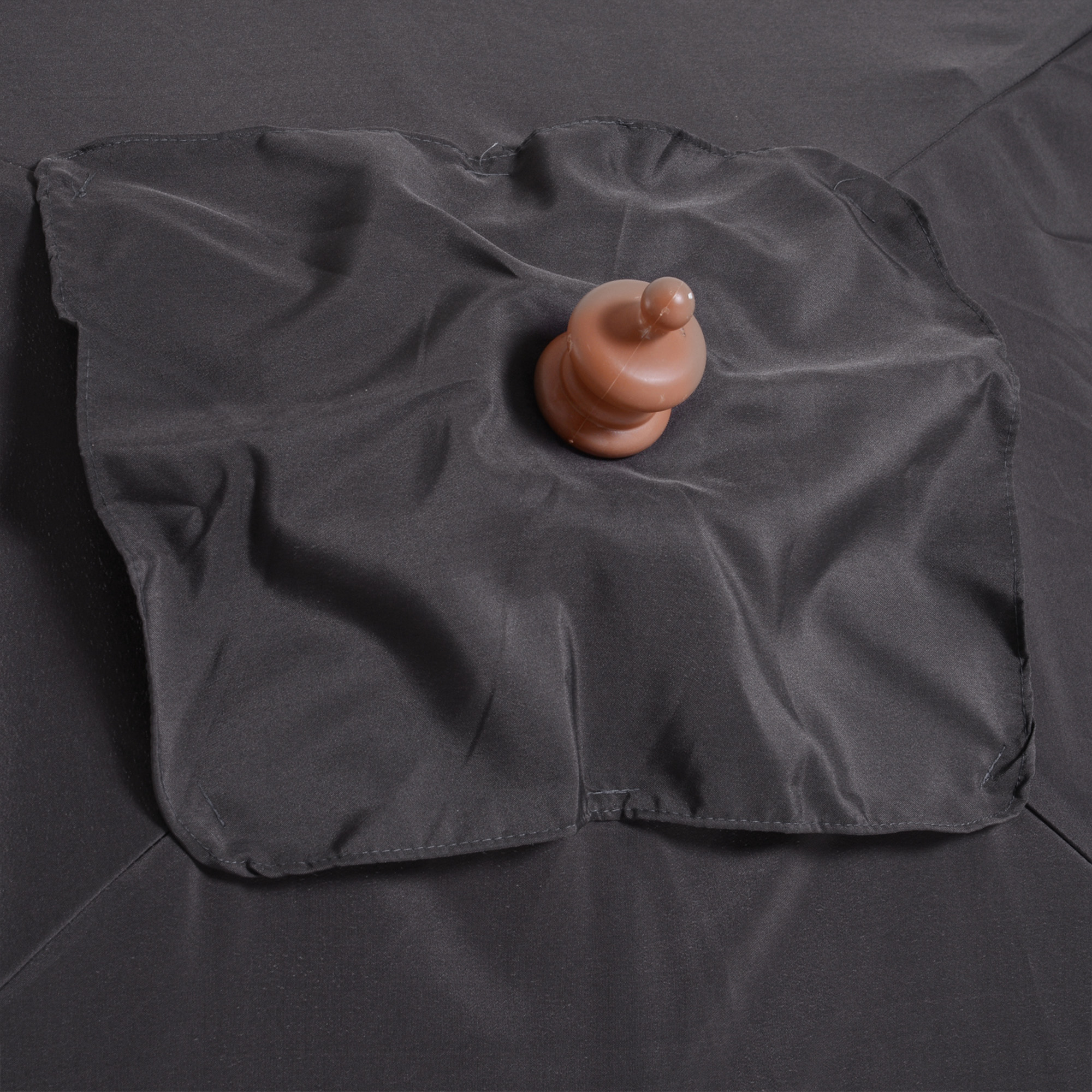 Un tappo di plastica marrone poggia su tessuto scuro e rugoso.
