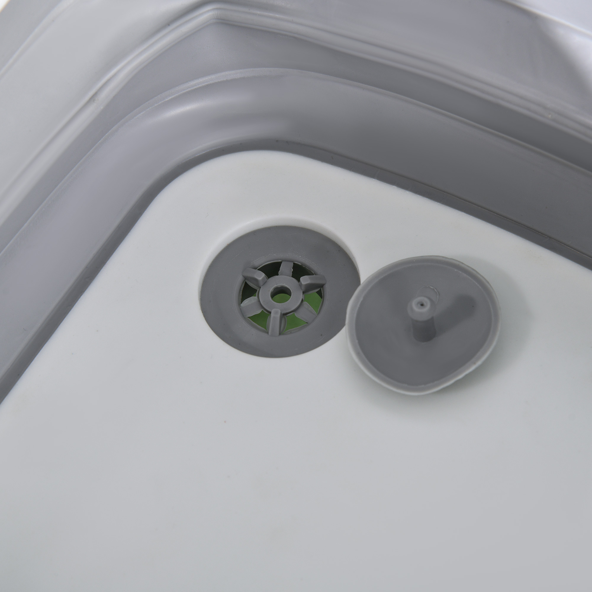 Desagüe gris con insertos y tapón separado en contenedor blanco.