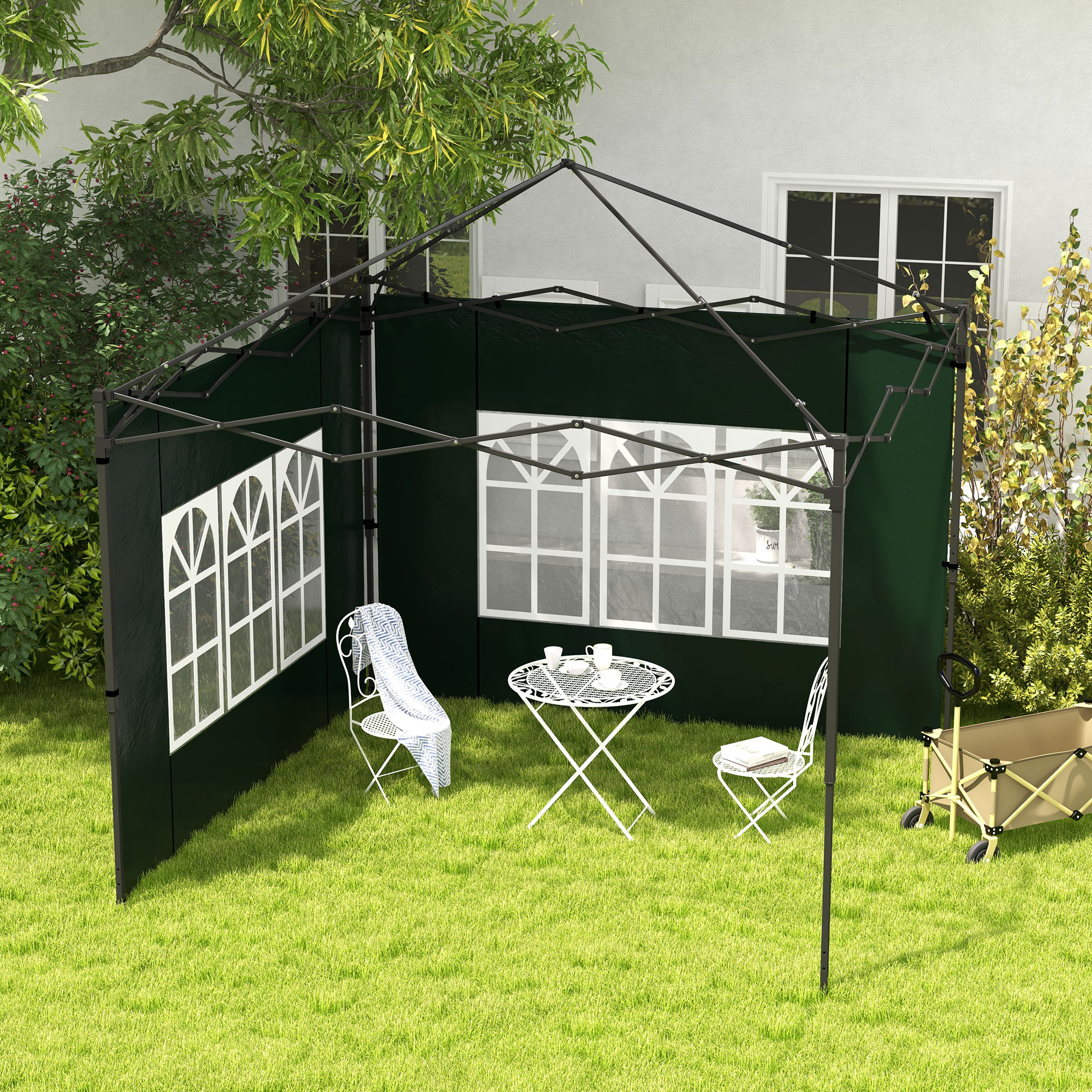 Una carpa verde oscura con ventanas se alza sobre césped, con muebles y un carro cerca.
