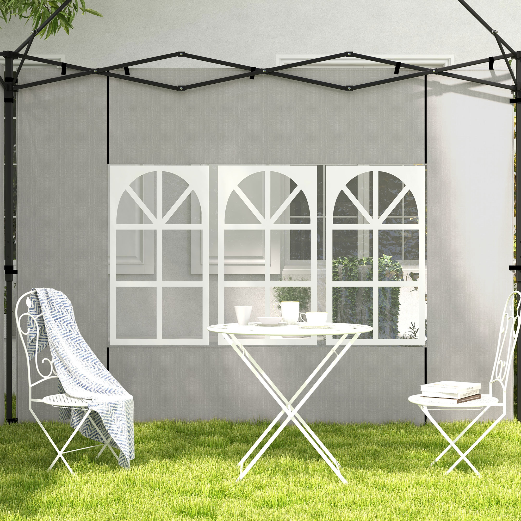 Mesa blanca de jardín con tazas, dos sillas, una con manta, sobre césped.