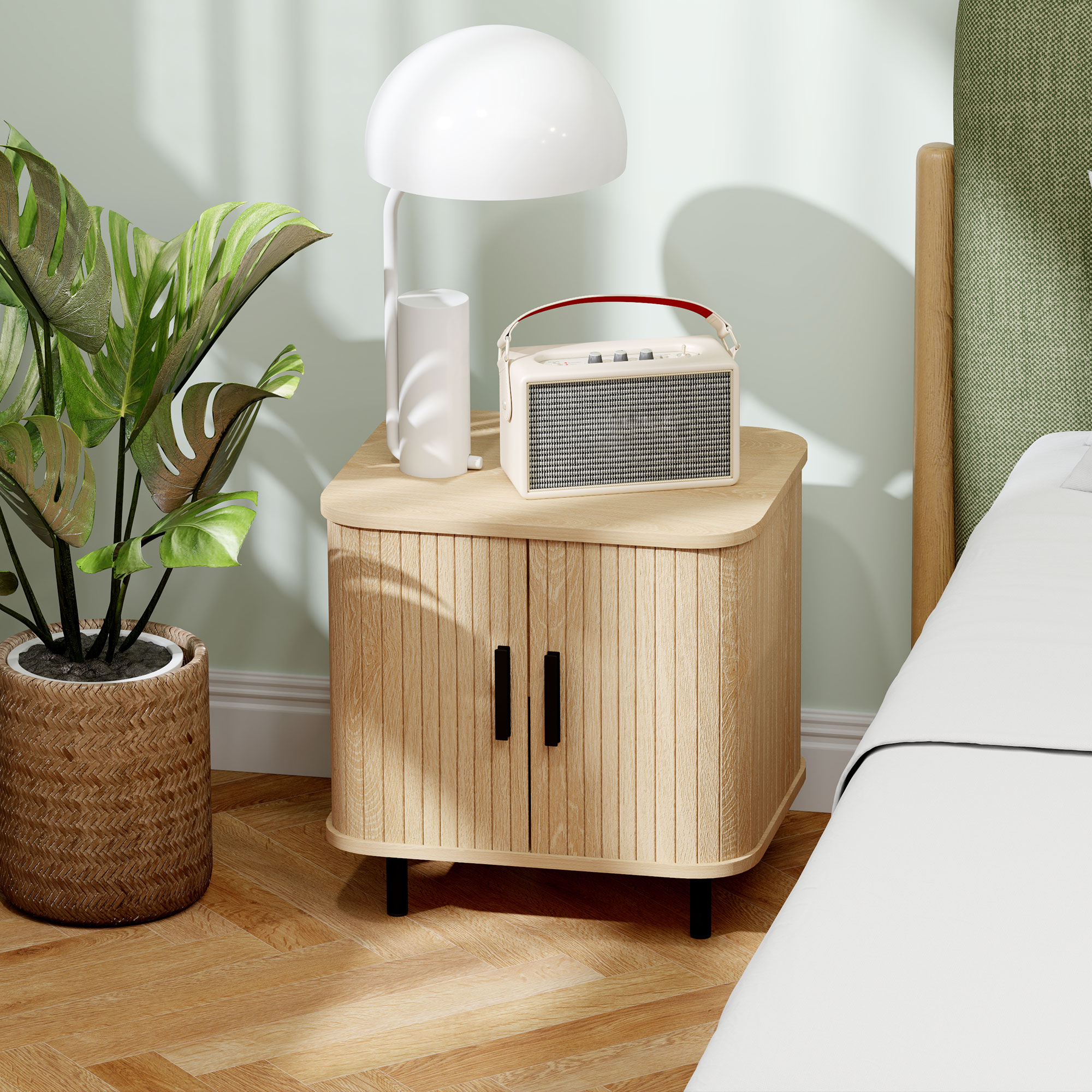 Planta, lámpara y radio en mesita de noche junto a cama.