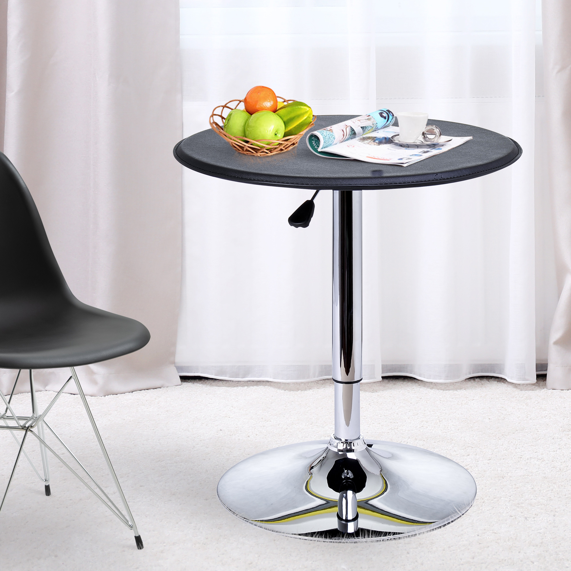 Una silla negra junto a una mesa redonda con fruta y una taza.