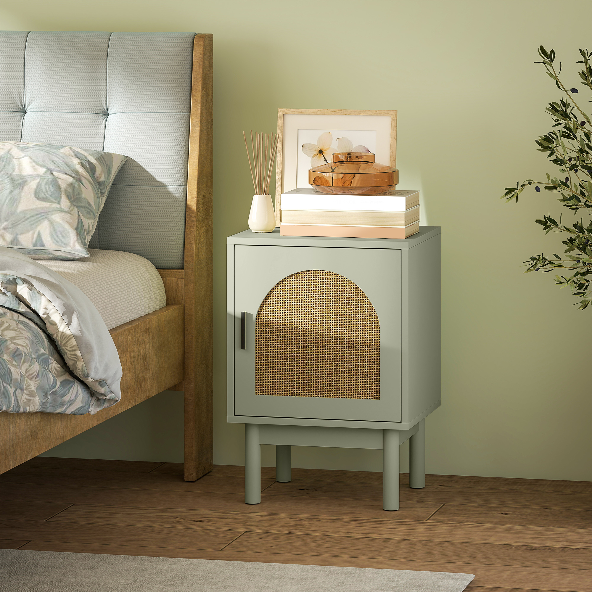 Una mesita de noche verde claro con puerta de ratán, junto a una cama.