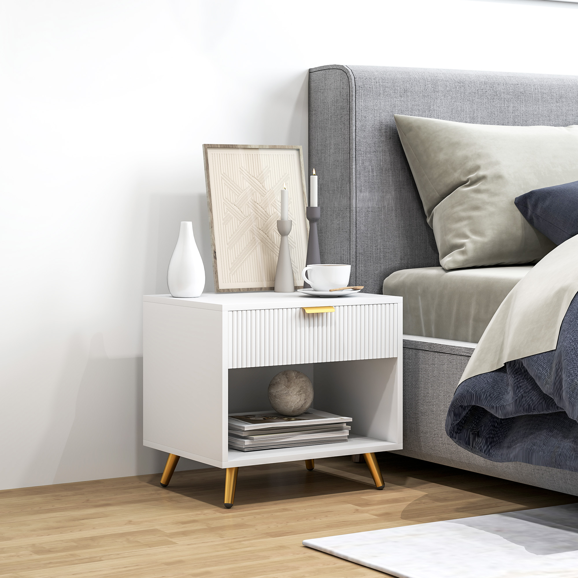 Una mesita de noche blanca con decoración, junto a una cama con cabecero gris.