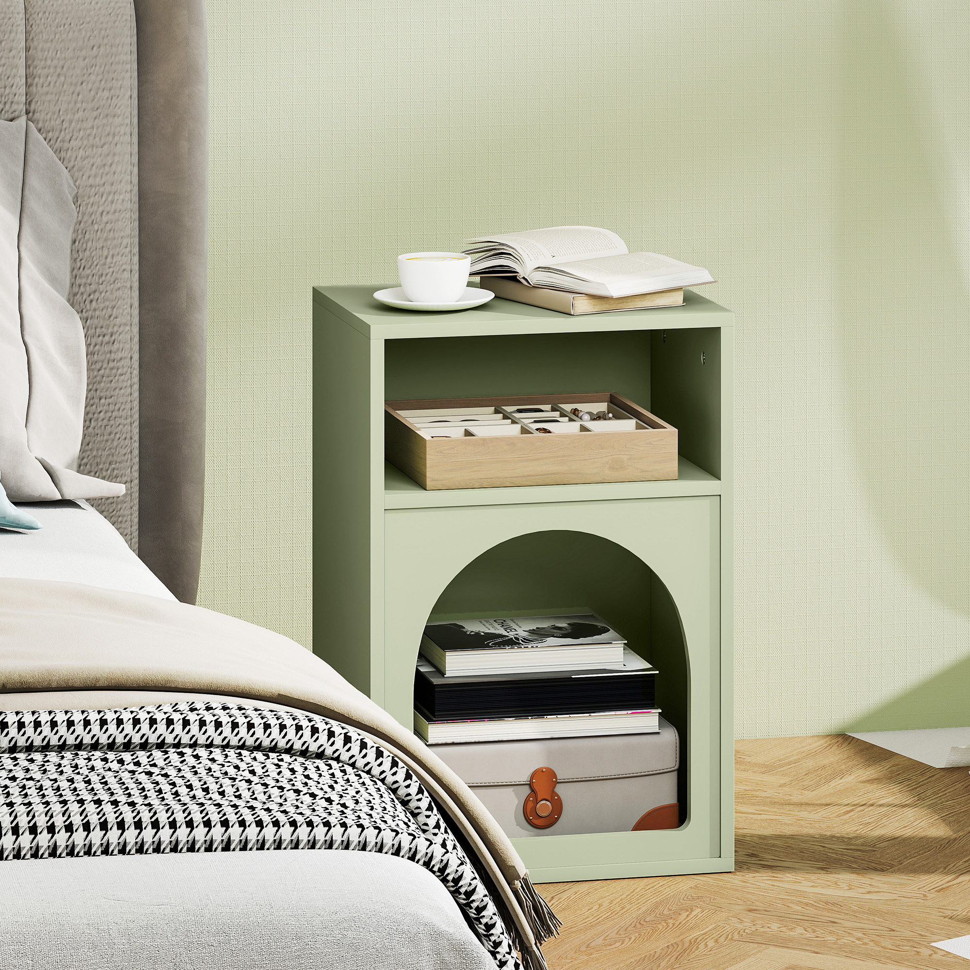 Una mesita de noche de madera verde claro con libros, una taza y una caja de joyas.