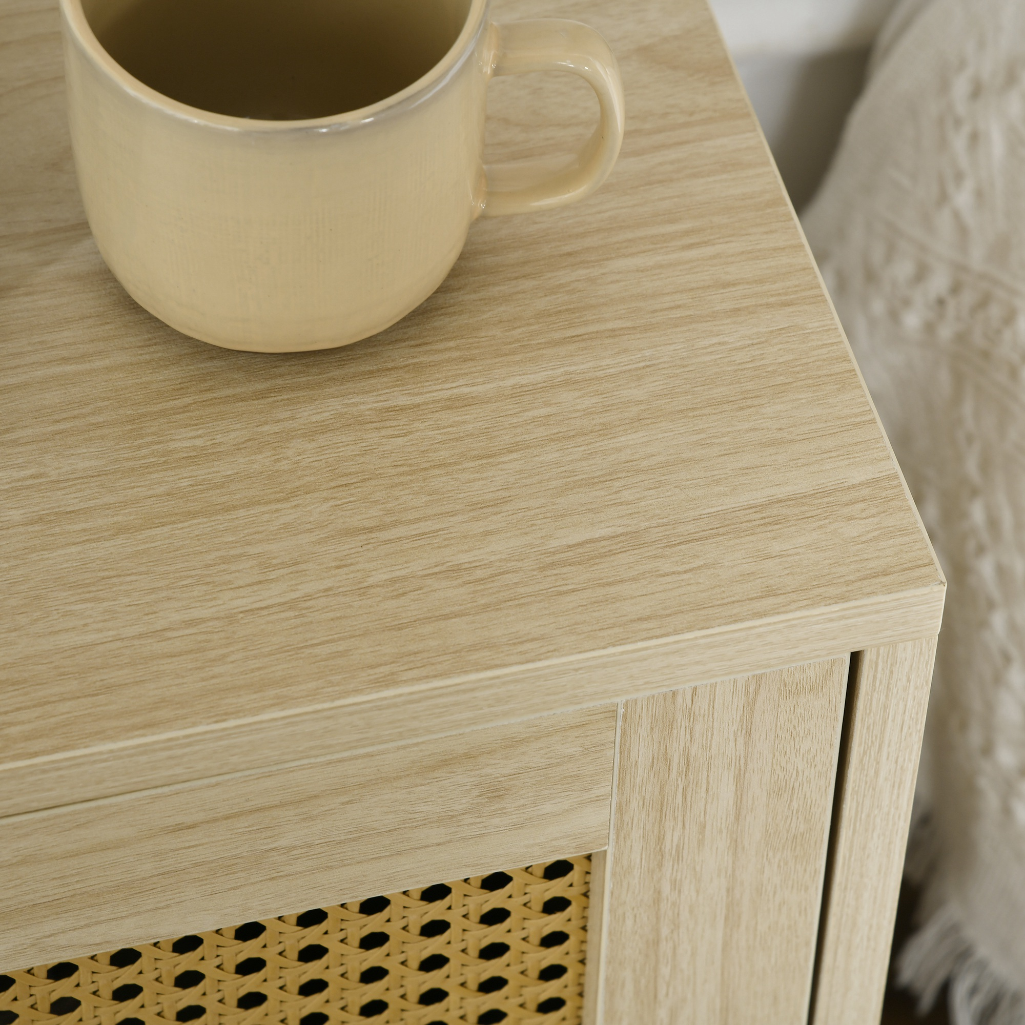 Una taza beige sobre una mesa de madera marrón claro con inserción de ratán.